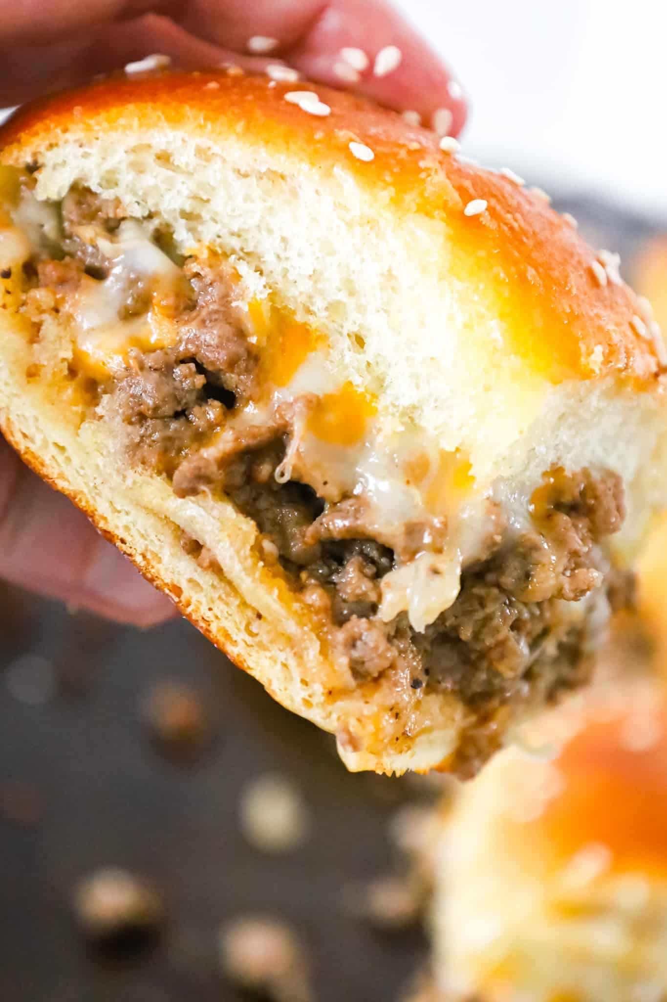 Cheeseburger Sliders are mini sandwiches made with crumbled ground beef and diced onions tossed in ketchup, mayo and mustard all loaded onto dinner rolls and topped with shredded cheese.