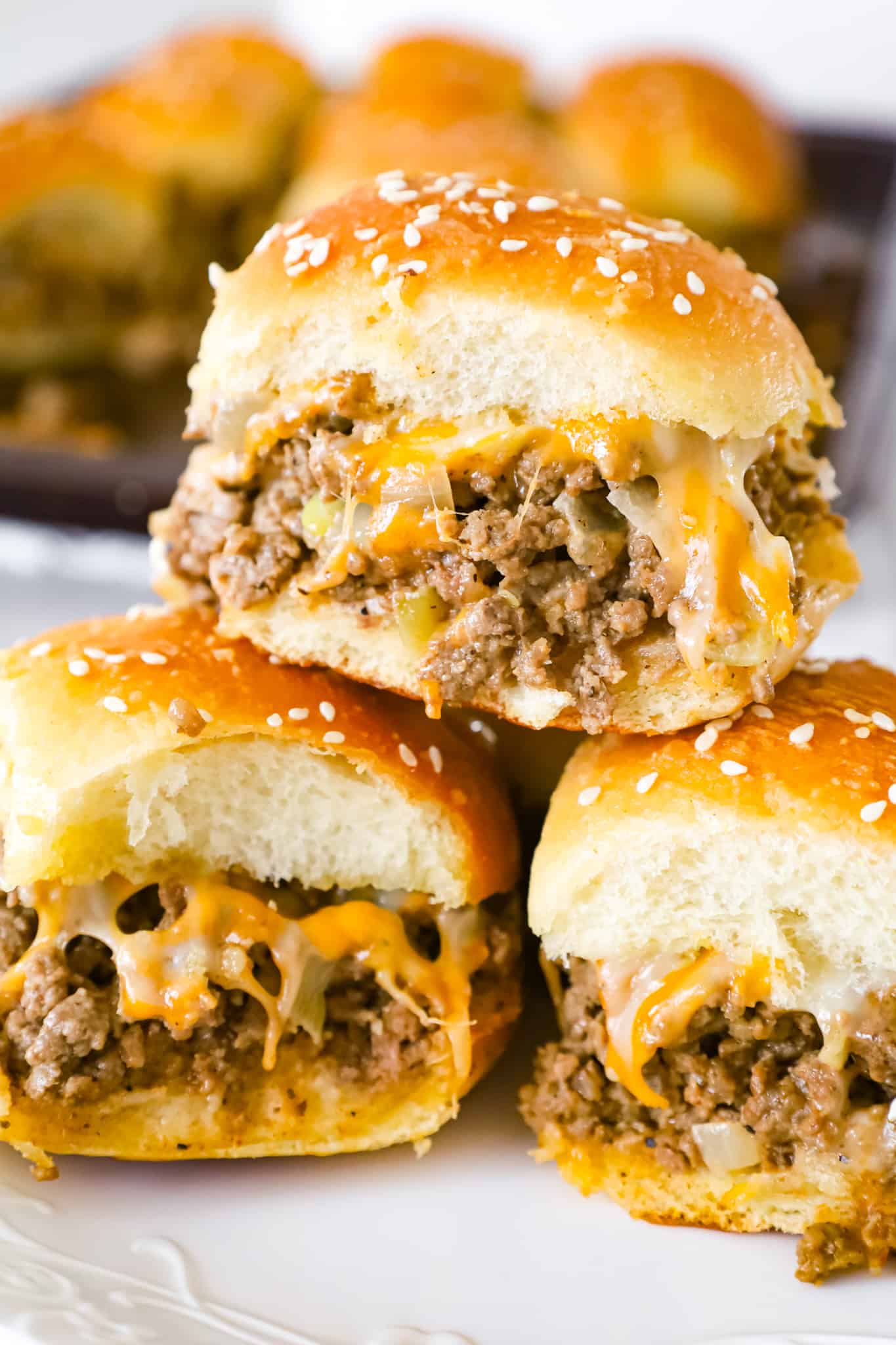 Cheeseburger Sliders are mini sandwiches made with crumbled ground beef and diced onions tossed in ketchup, mayo and mustard all loaded onto dinner rolls and topped with shredded cheese.