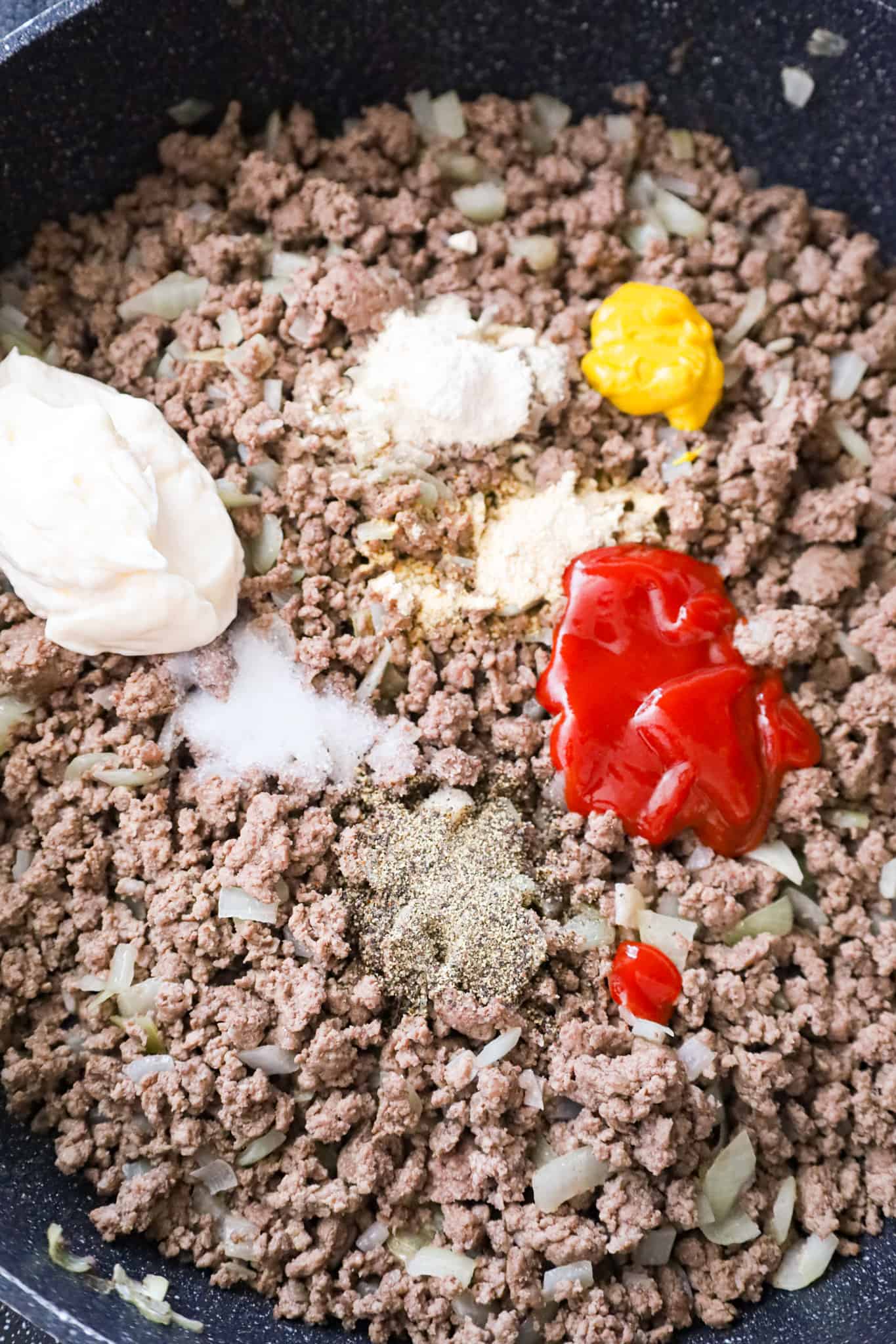 mayo, ketchup, mustard and spices on top of cooked ground beef in a saute pan