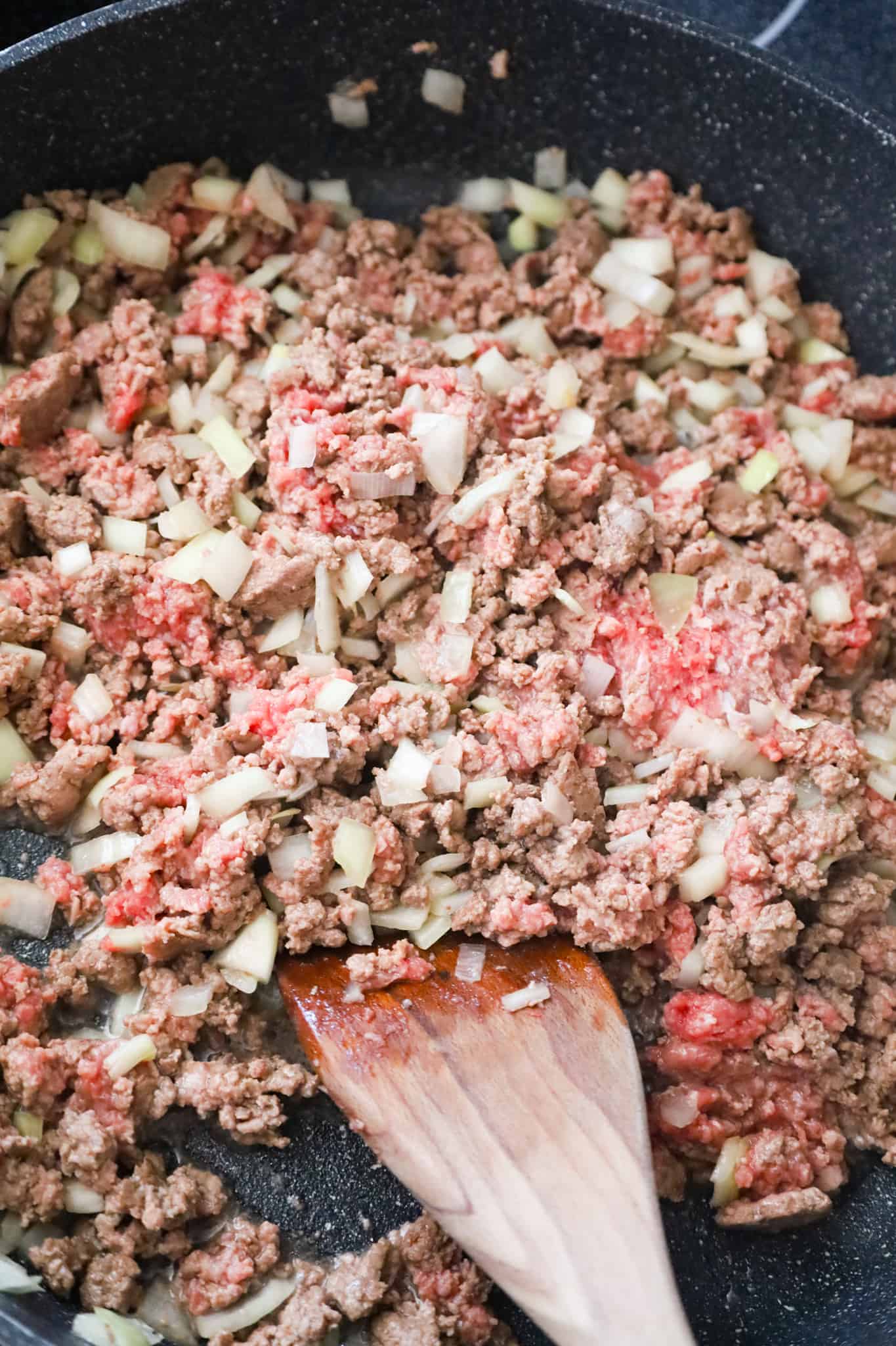 ground beef and diced onions cooking in a saute pan