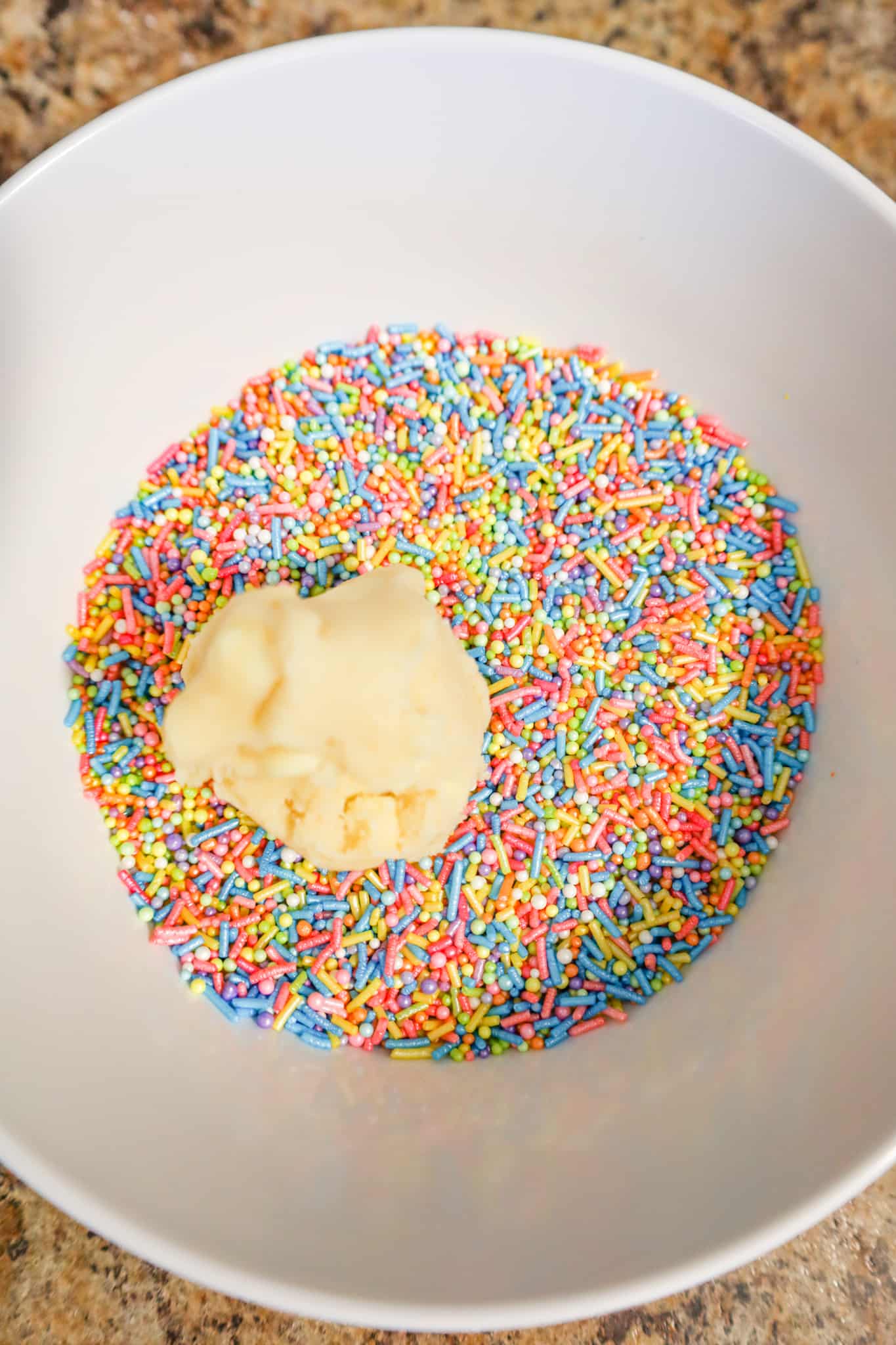 ball of cookie dough in a bowl of rainbow sprinkles