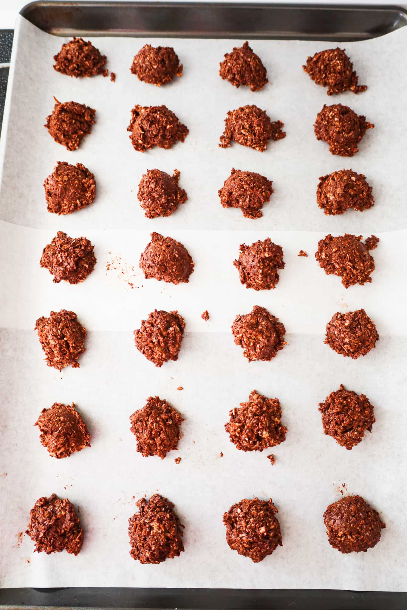 spoonfuls of chocolate oat mixture on a parchment lined baking sheet