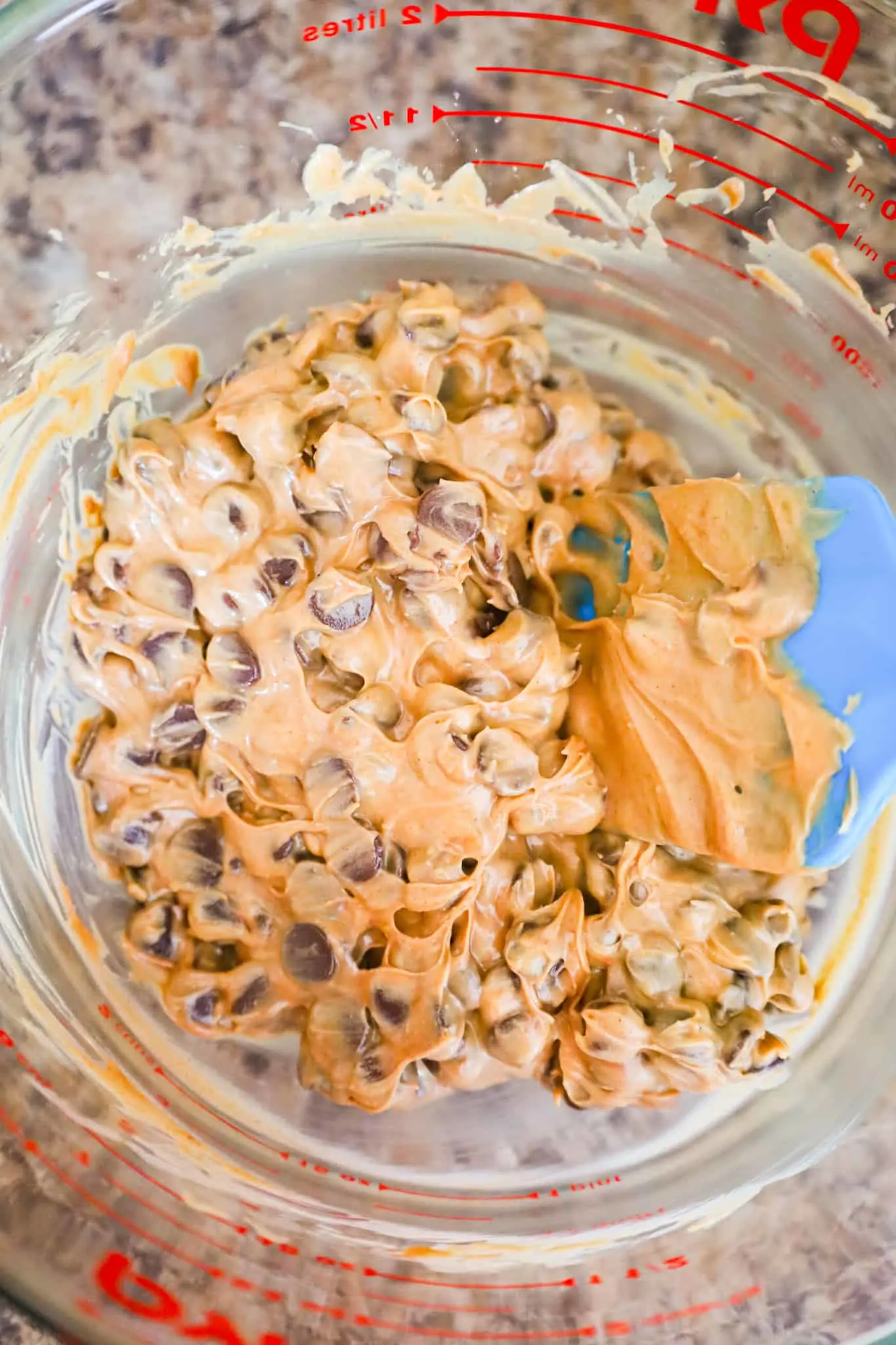 peanut butter and chocolate chips being stirred together in a glass bowl