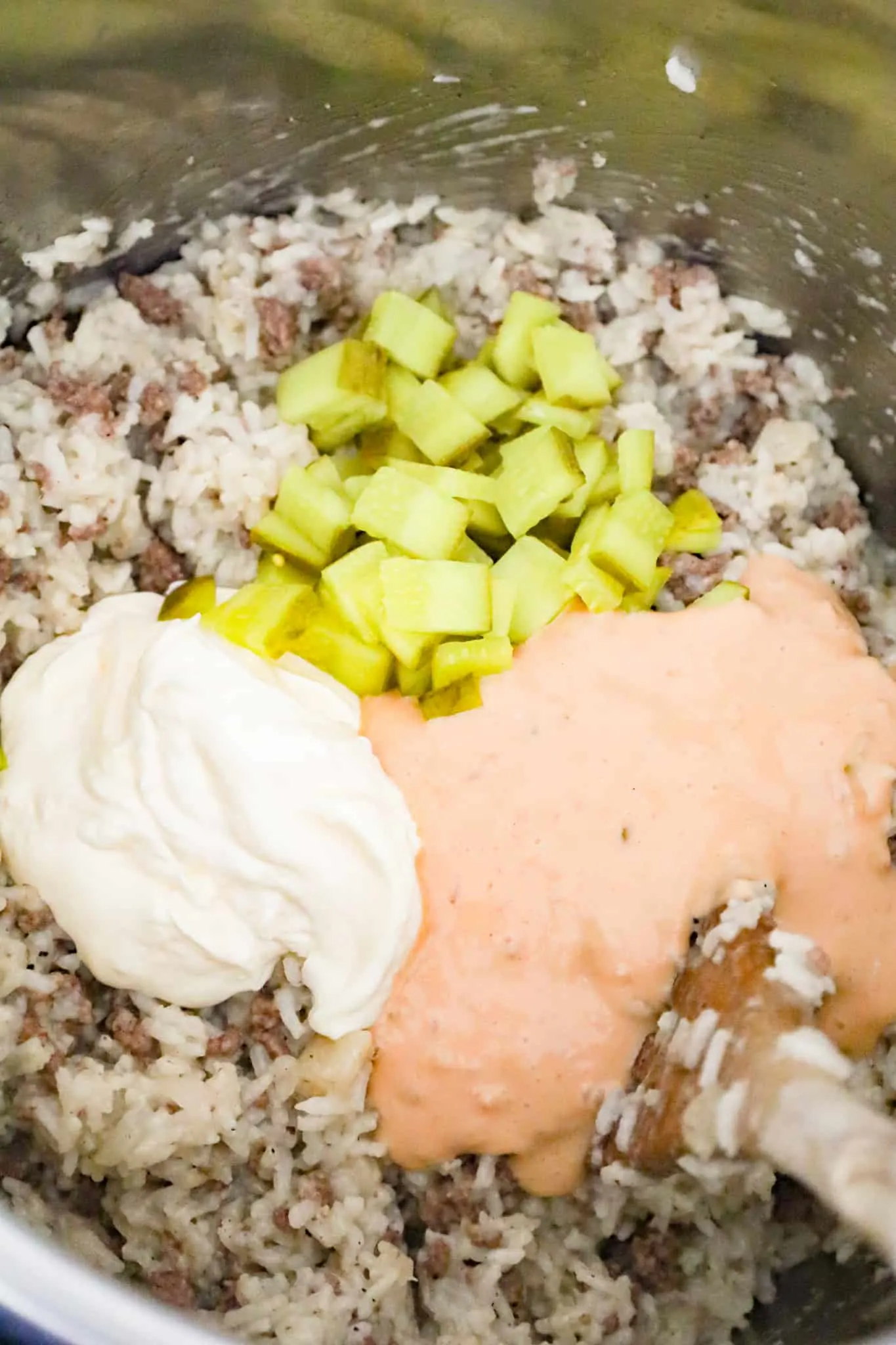 diced dill pickles, mayo and Thousand Island dressing on top of cooked ground beef and rice in an Instant Pot