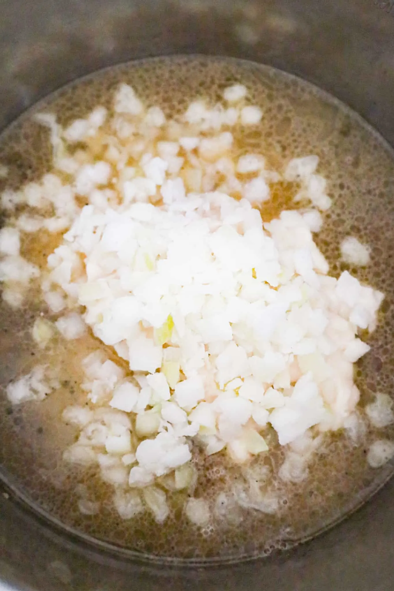 diced onions on top of broth and ground beef mixture in an Instant Pot