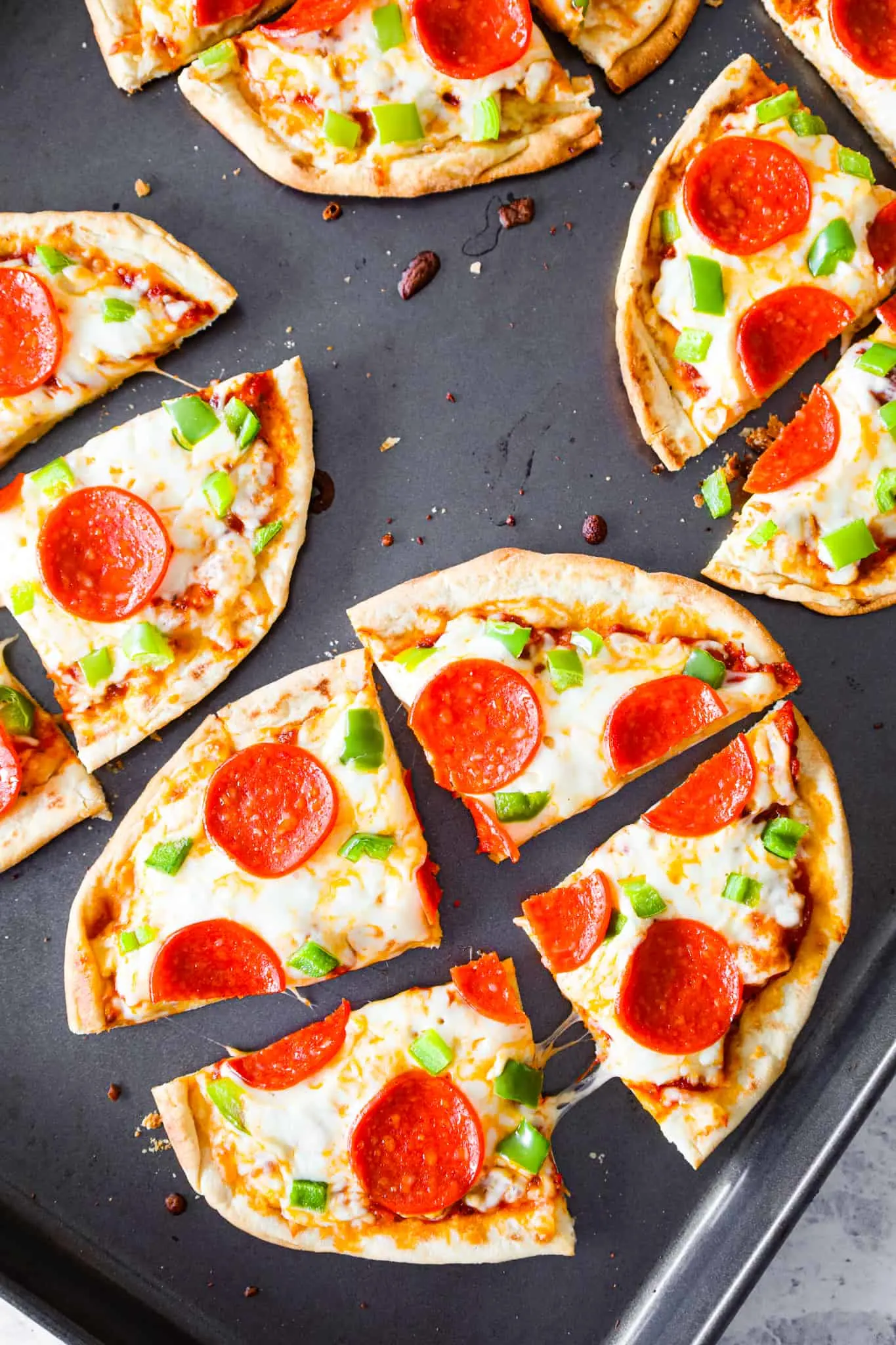 Naan Pizza is an easy dinner recipe using store bought naan bread topped with pizza sauce, shredded mozzarella cheese, sliced pepperoni and diced green peppers.