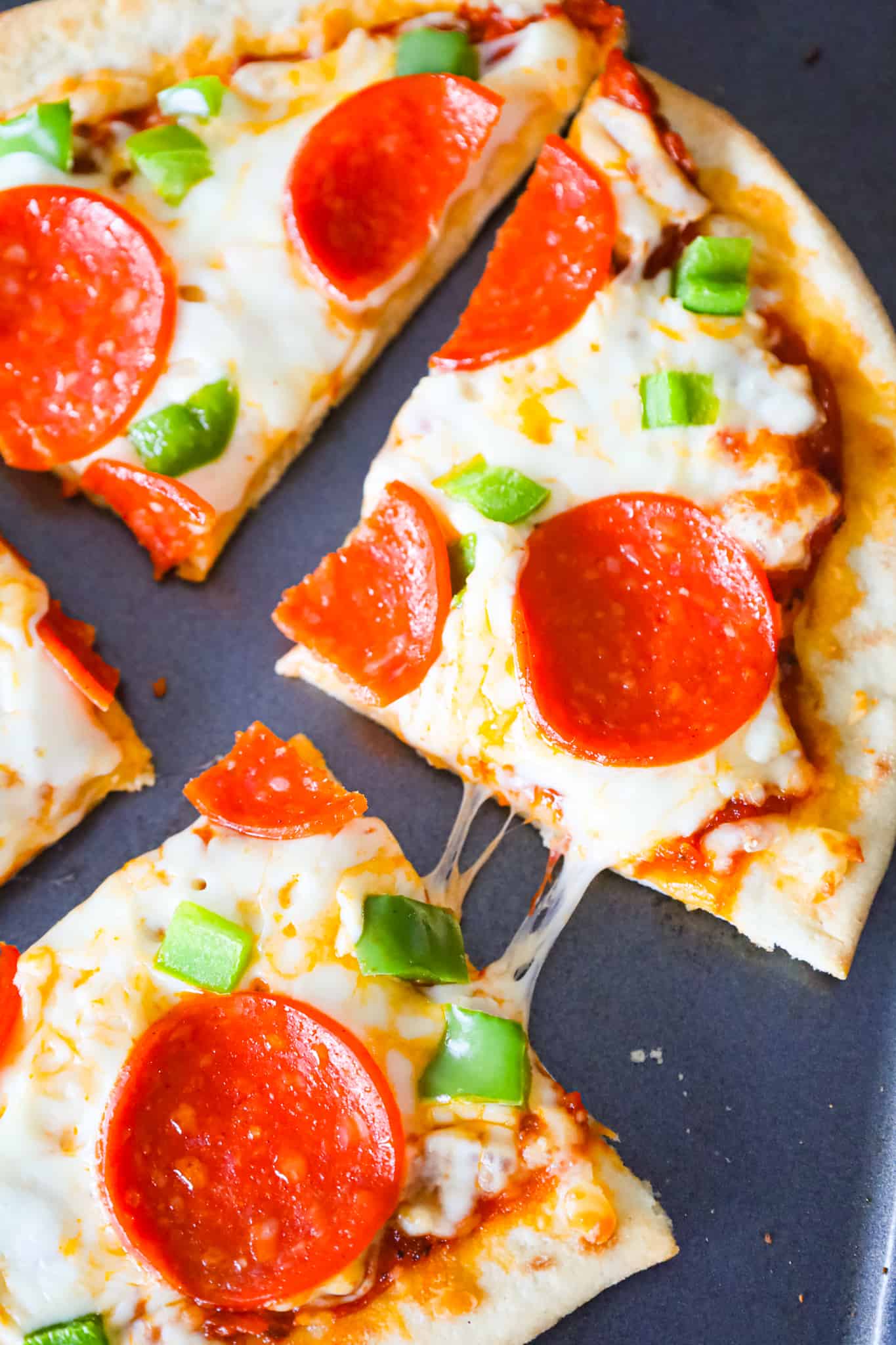 Naan Pizza is an easy dinner recipe using store bought naan bread topped with pizza sauce, shredded mozzarella cheese, sliced pepperoni and diced green peppers.
