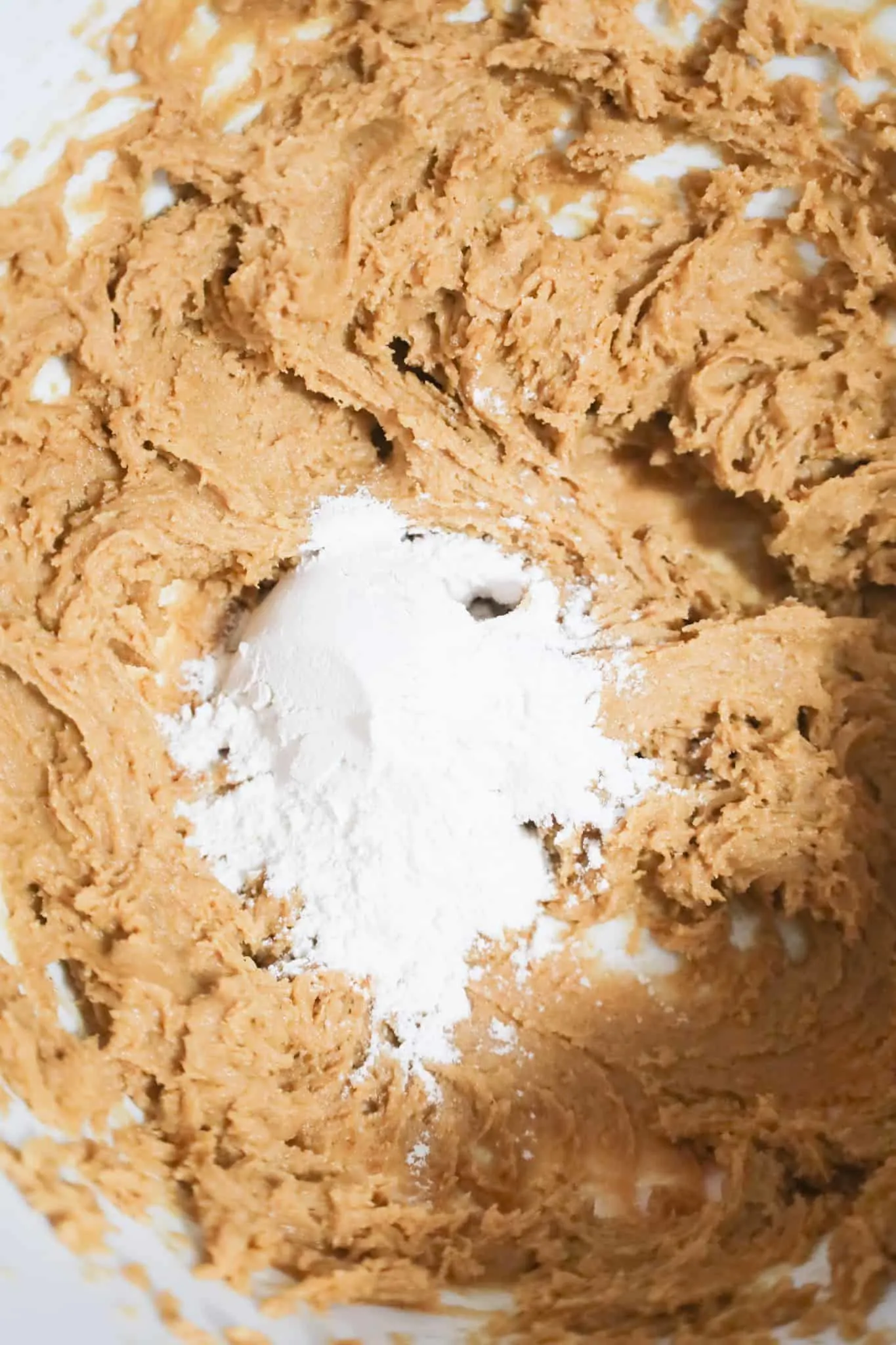 all purpose flour on top of creamy peanut butter mixture in a mixing bowl