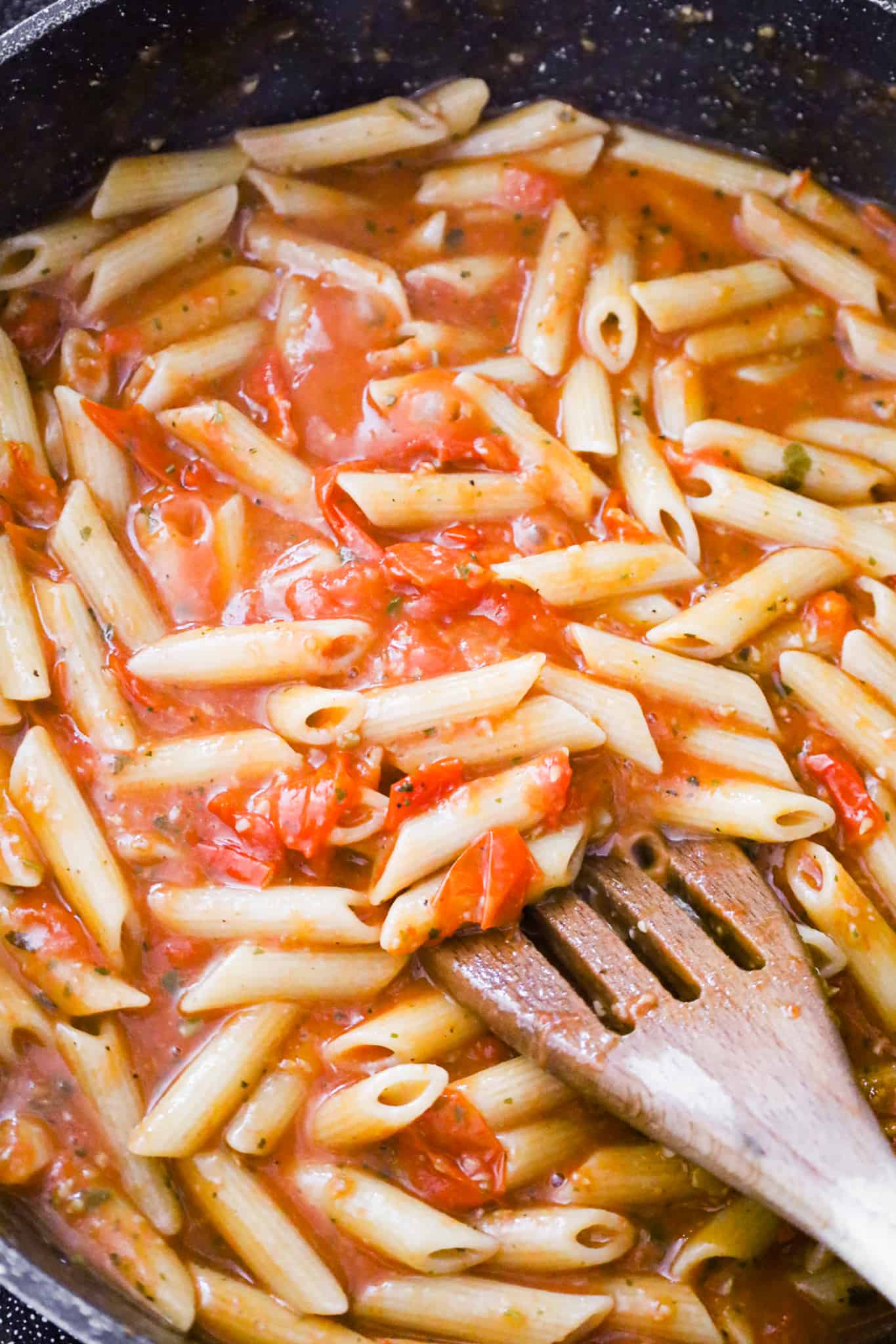penne noodles tossed in tomato sauce in a pan