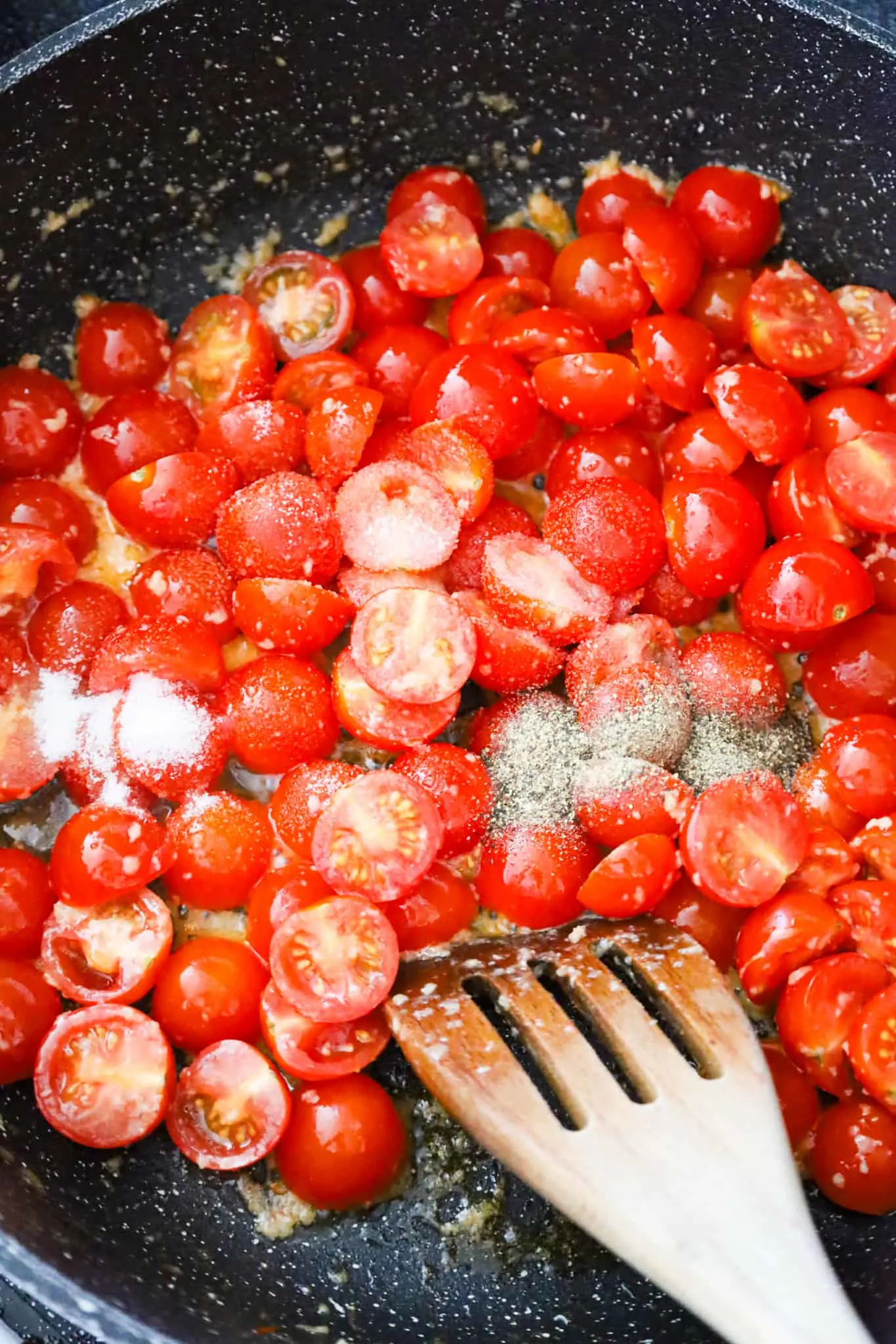 salt, pepper and sugar on top of halved cherry tomatoes in a saute pan
