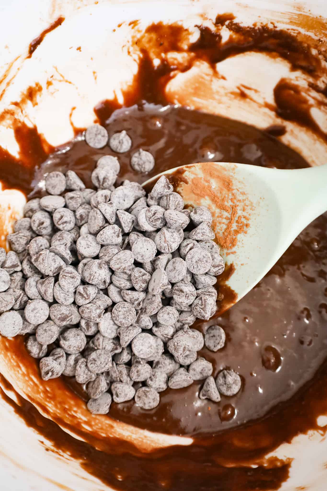 chocolate chips on top of brownie batter in a mixing bowl