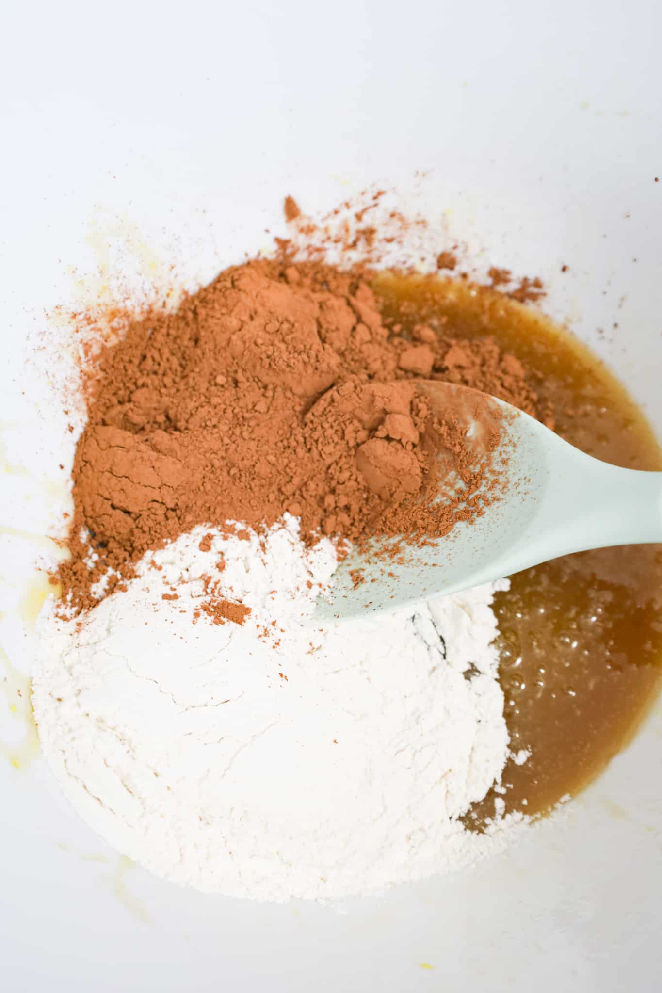 cocoa powder and flour on top of melted butter and brown sugar mixture in a mixing bowl