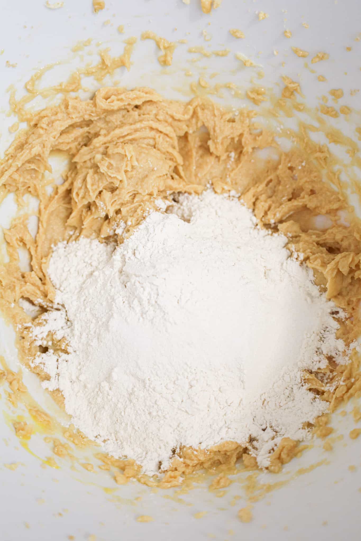 flour on top of creamed butter and sugar mixture in a mixing bowl