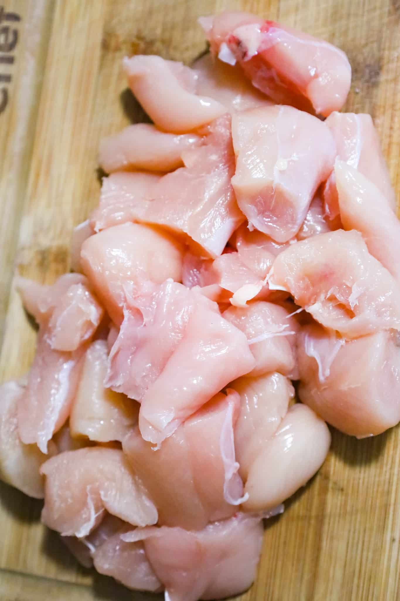 raw chicken breast chunks on a cutting board