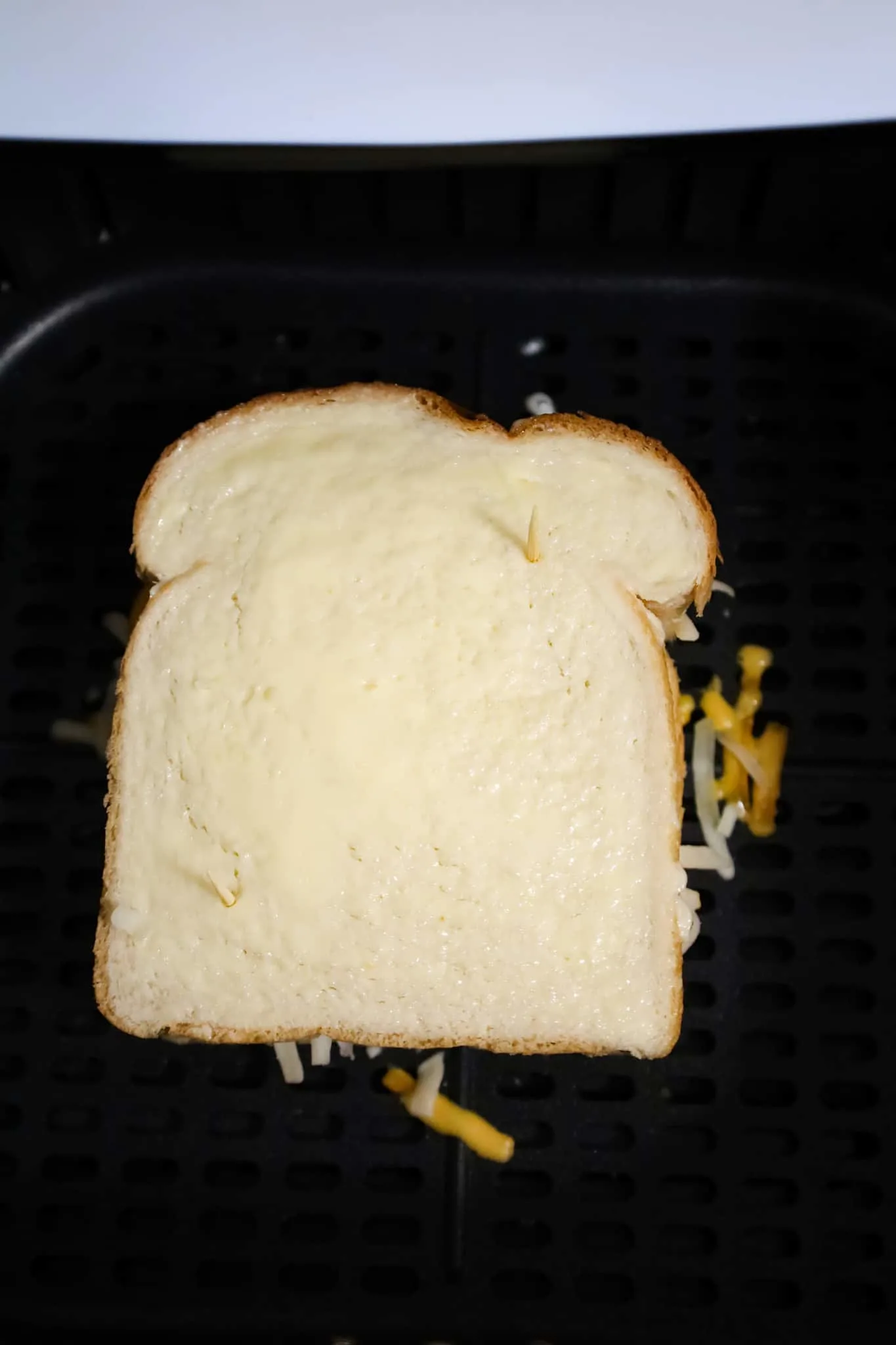 grilled cheese sandwich in air fryer basket before air frying