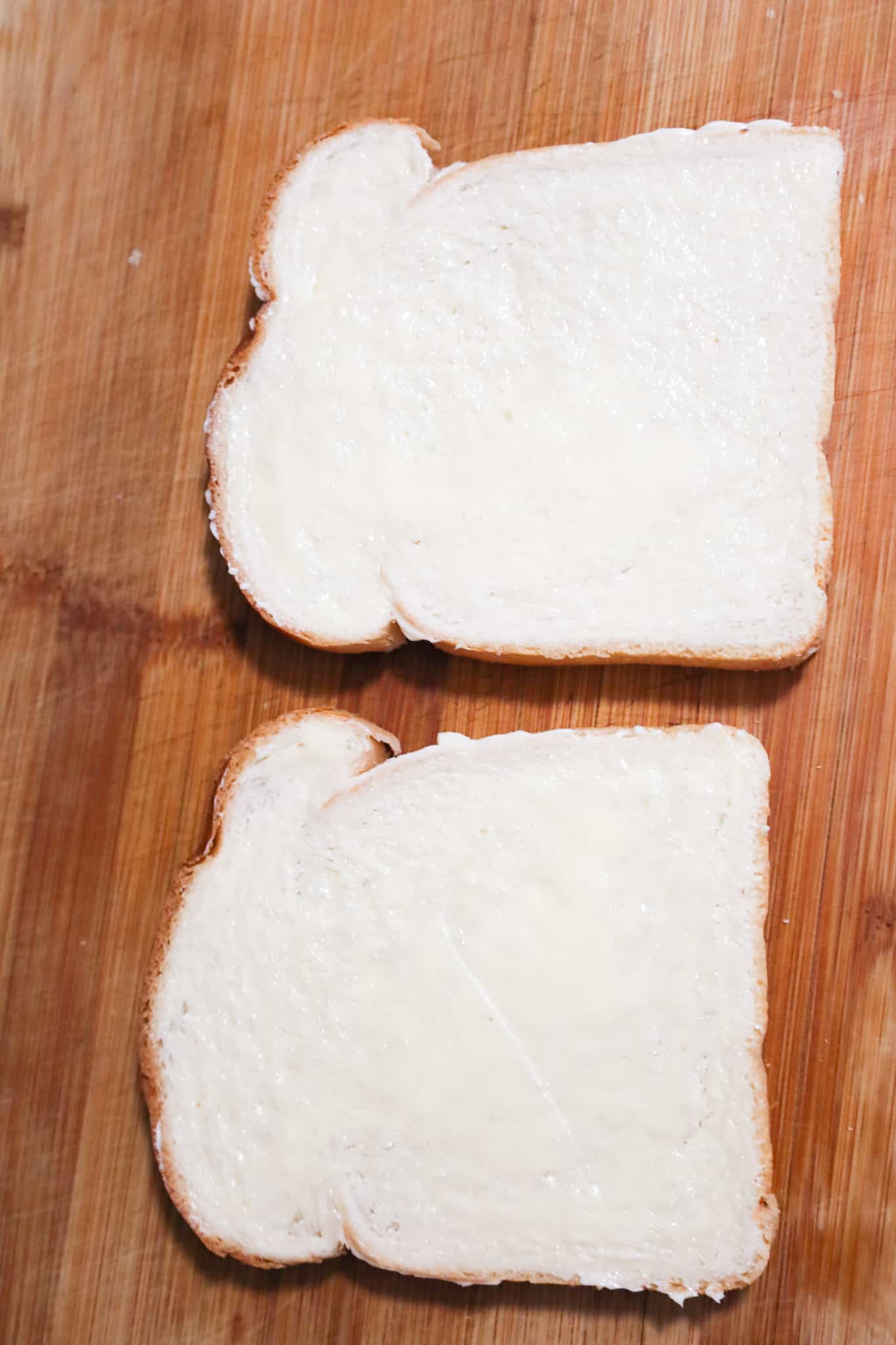 slices of bread on a cutting board spread with butter