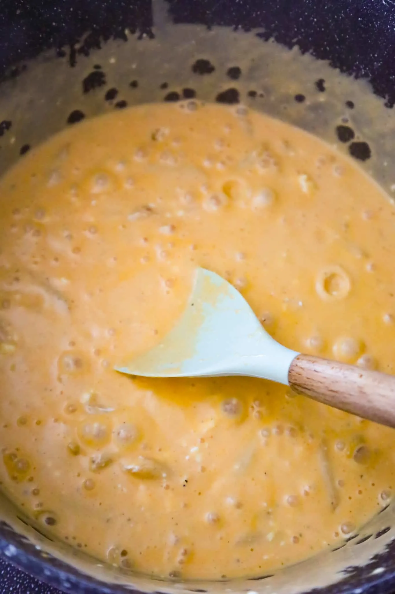 penne noodles cooking in a creamy buffalo sauce in a pot