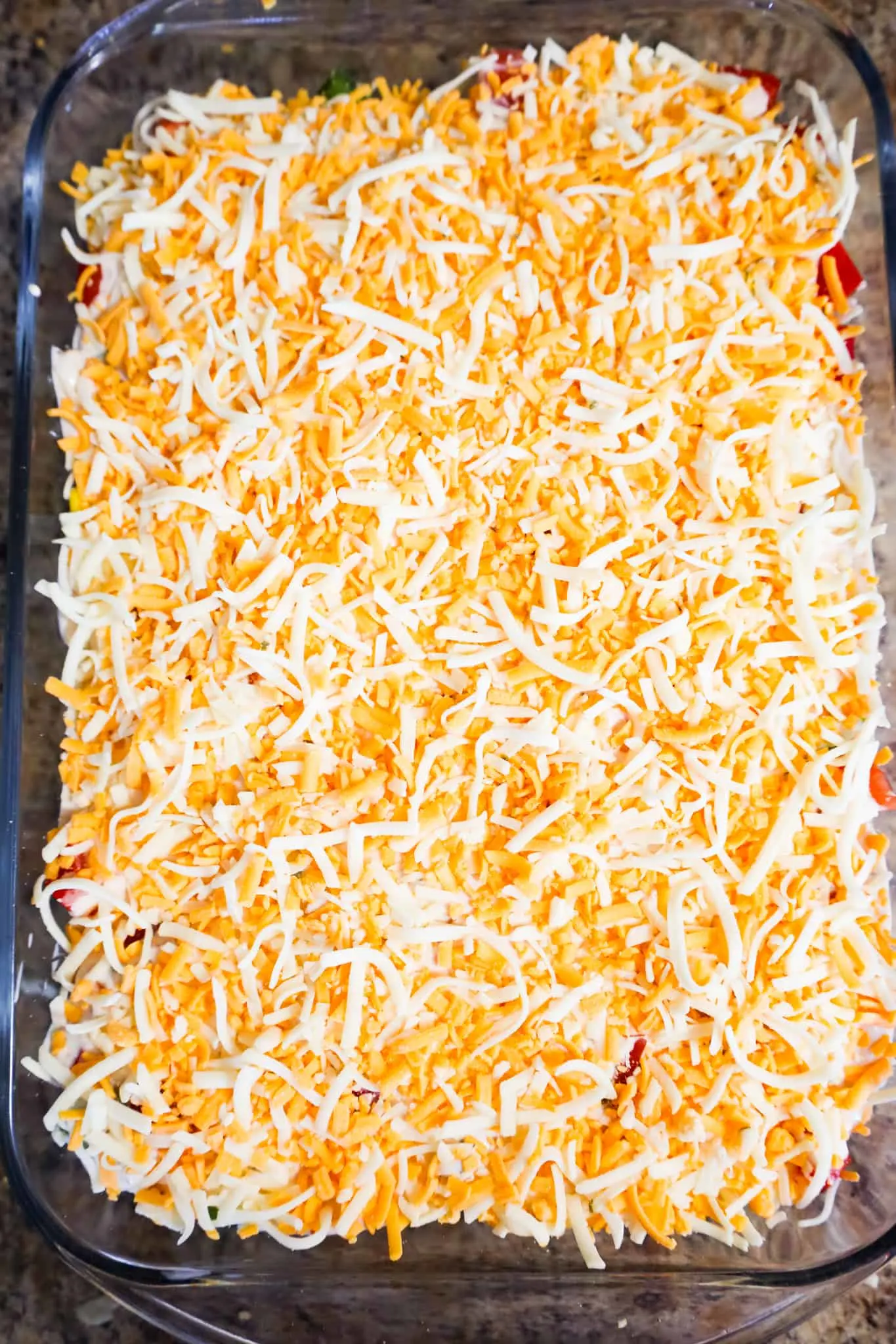 shredded cheese on top of cornbread salad in a baking dish