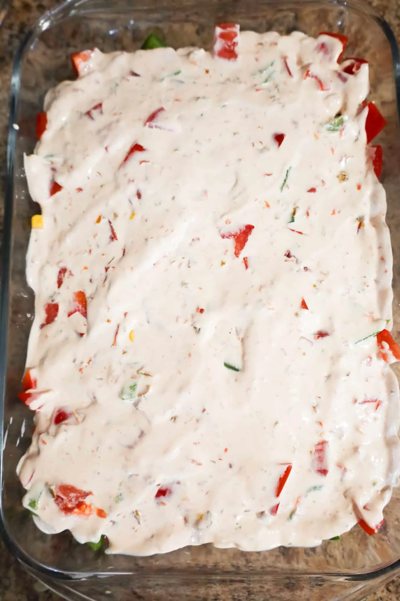 sour cream dressing mixture spread on top of vegetable mixture in a baking dish