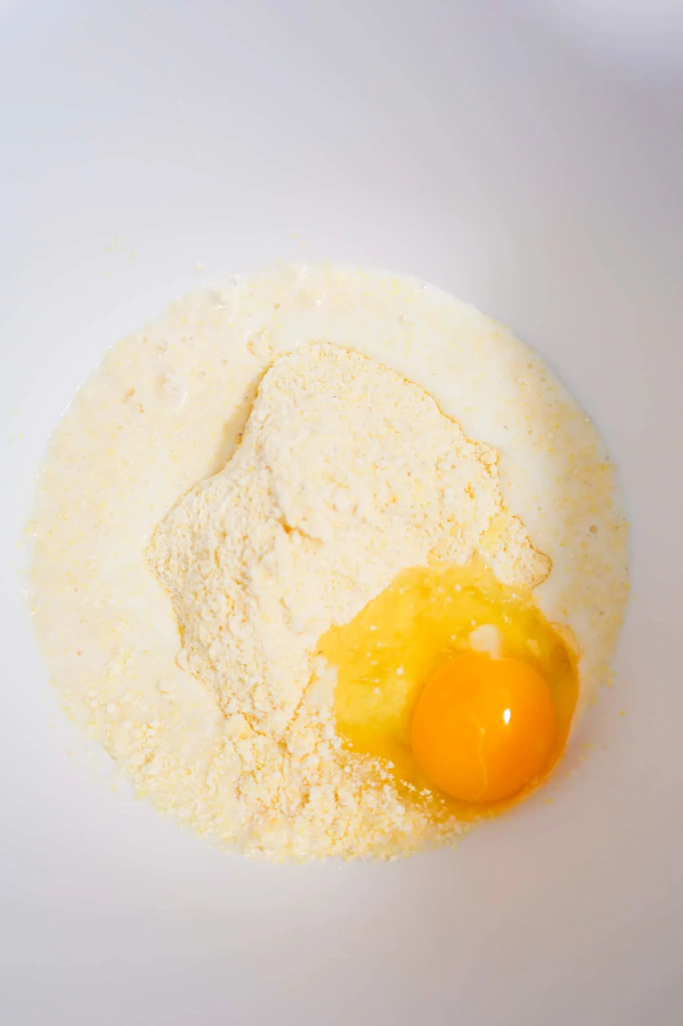cornbread mix, milk and an egg in a mixing bowl
