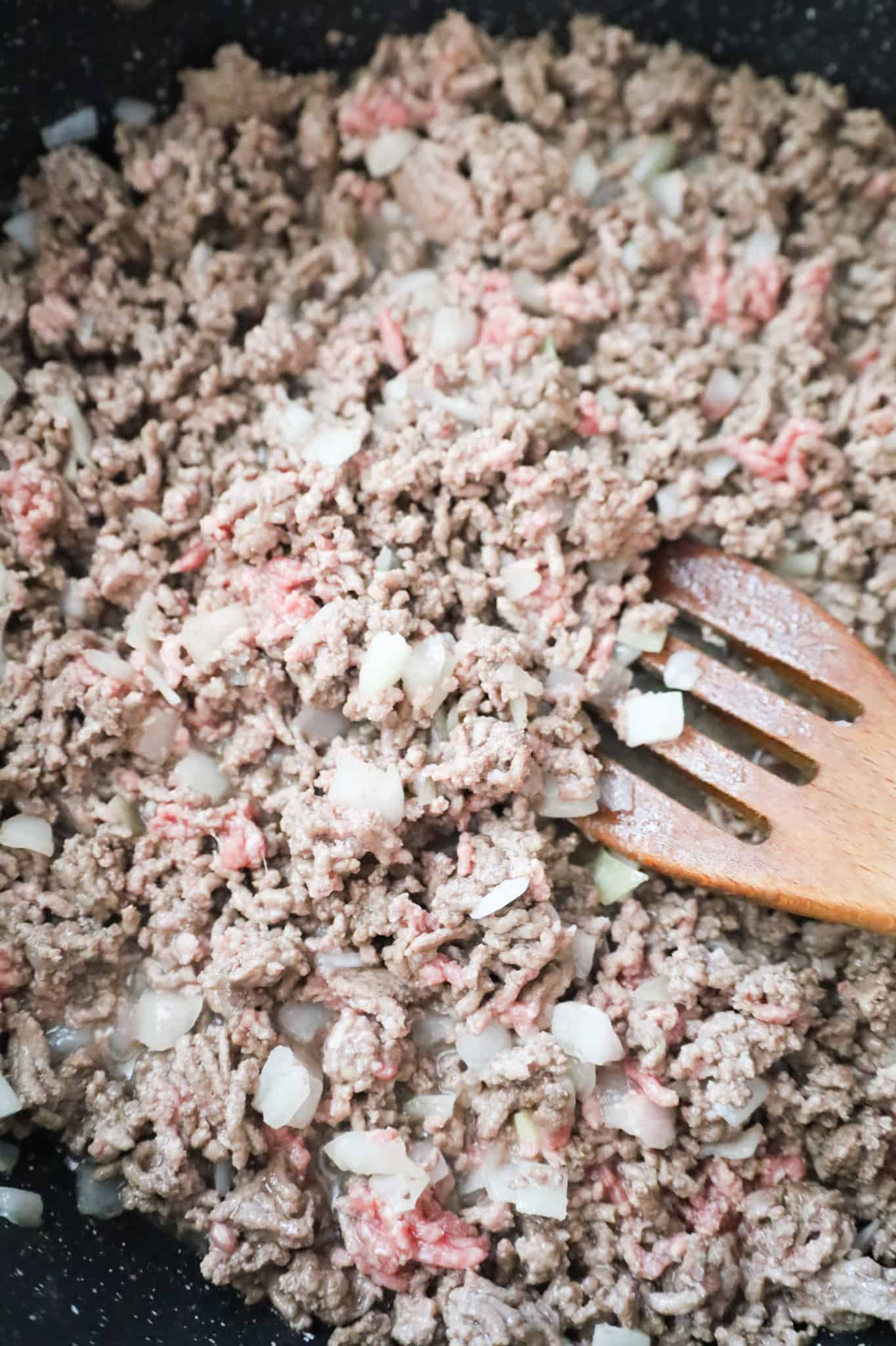 ground beef and diced onions cooking in a saute pan