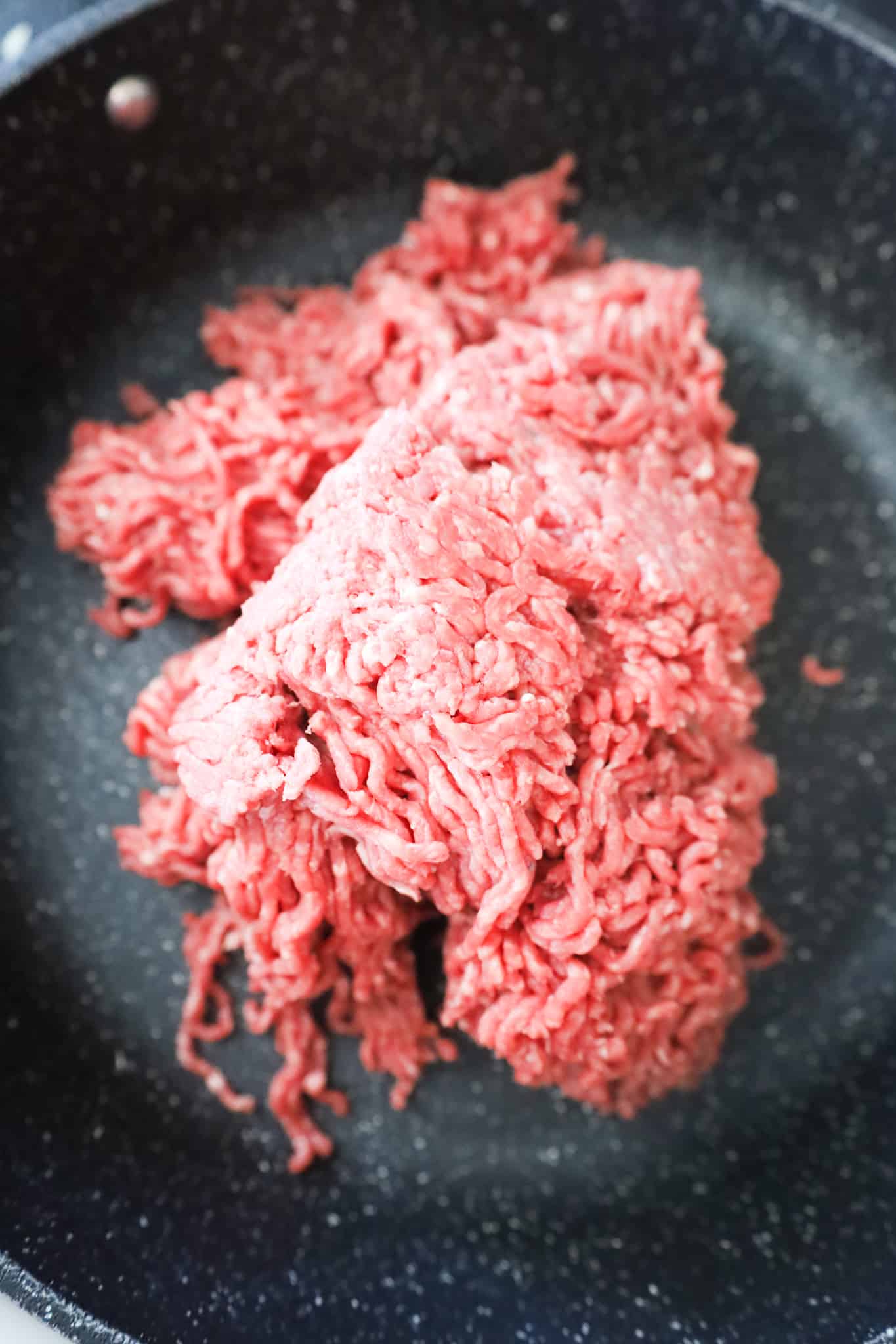 raw ground beef in a saute pan