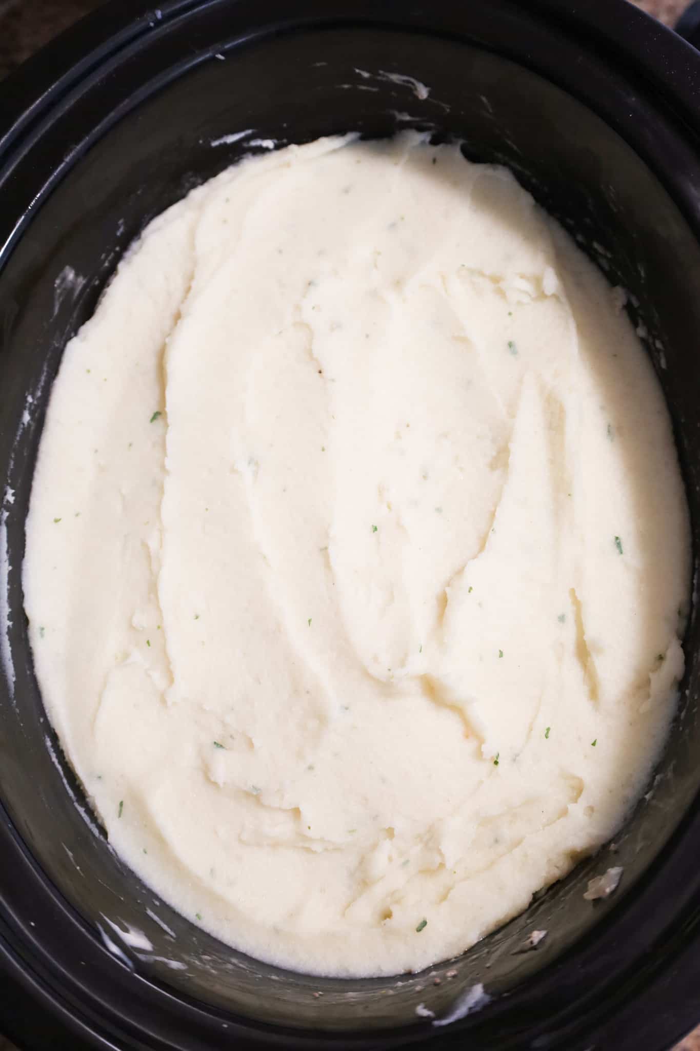mashed potatoes spread on top of ground beef mixture in a crock pot
