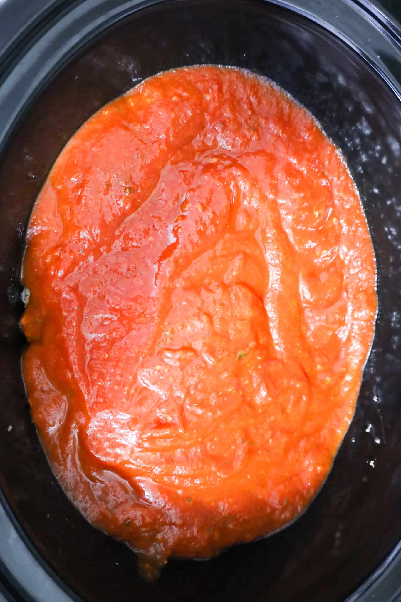 marinara sauce on top of cooked ground beef in a crock pot