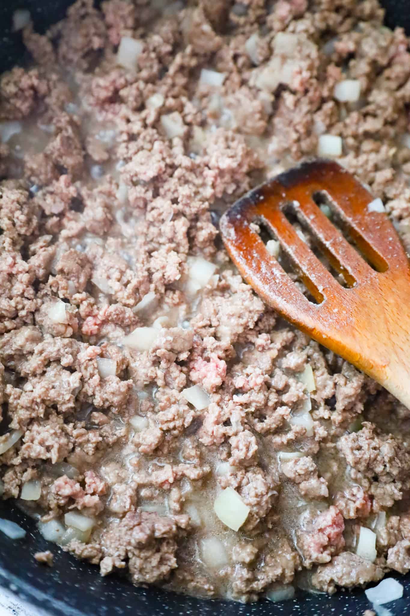 ground beef and diced onions cooking in a saute pan