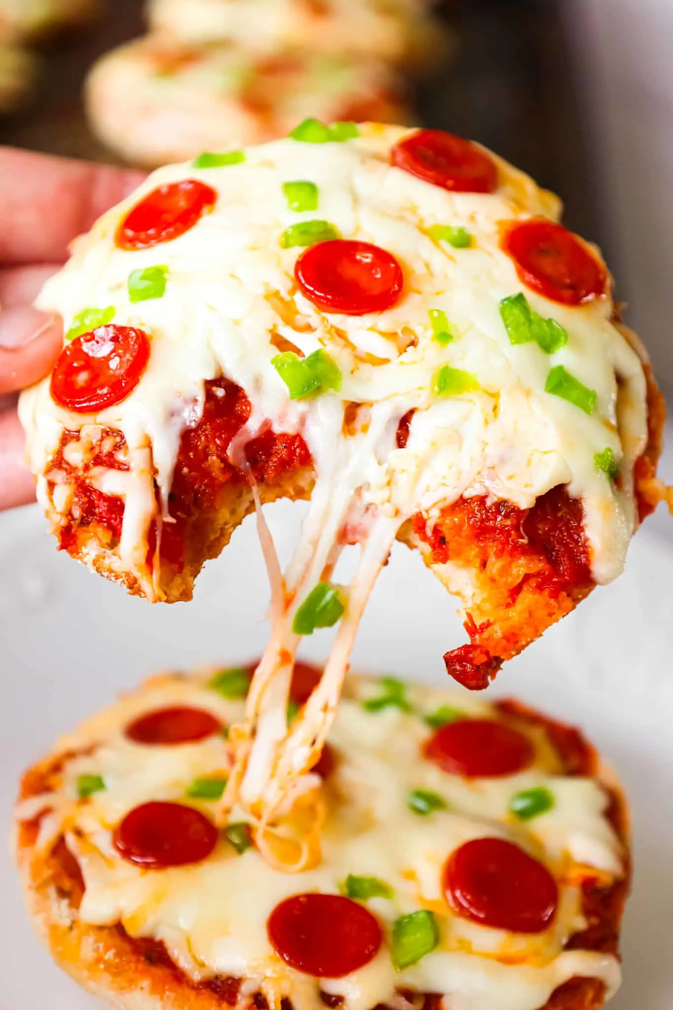 English Muffin Pizzas are an easy dinner recipe made with split English muffins topped with pizza sauce, shredded mozzarella cheese, mini pepperonis and diced green peppers.