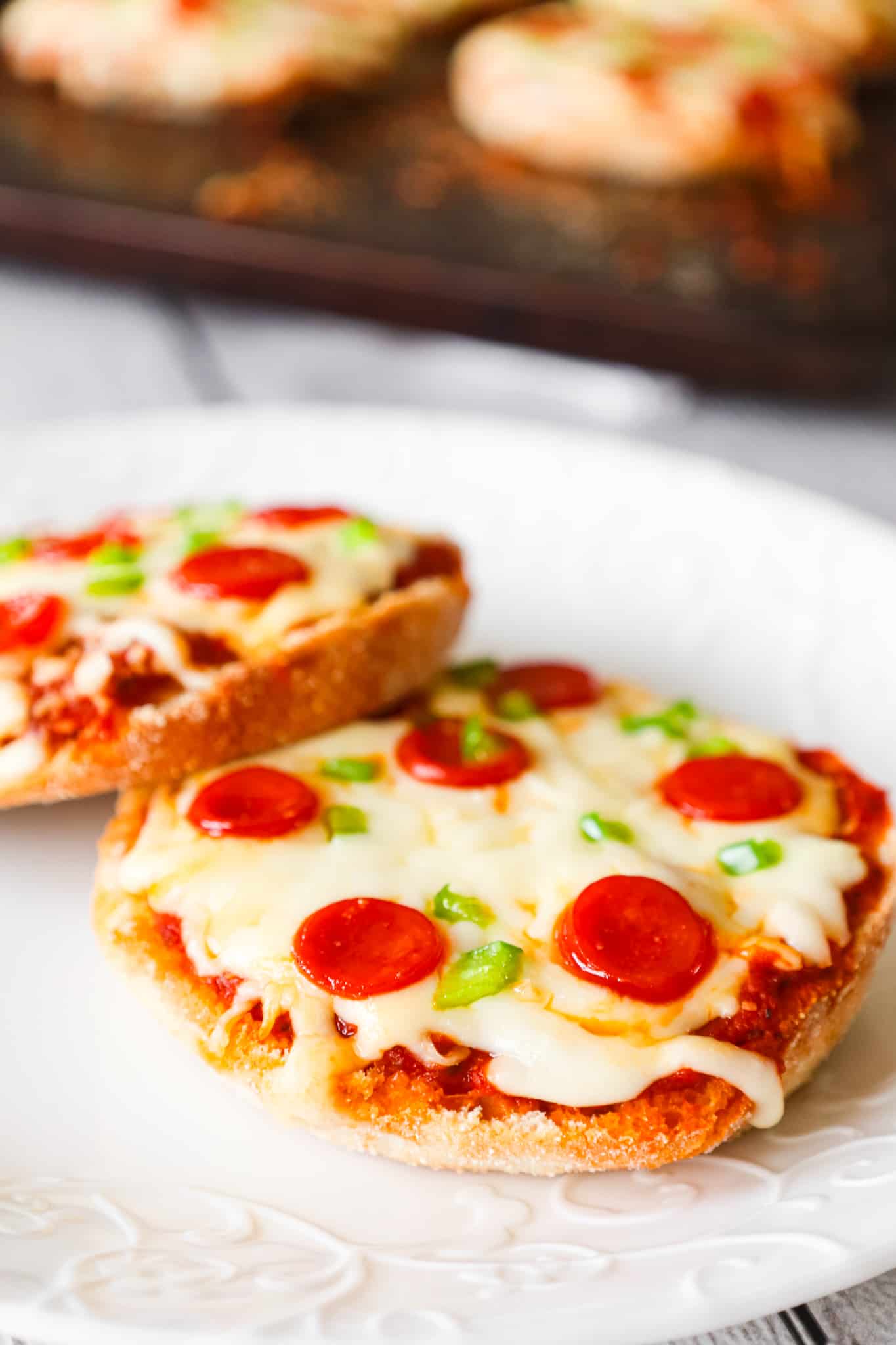 English Muffin Pizzas are an easy dinner recipe made with split English muffins topped with pizza sauce, shredded mozzarella cheese, mini pepperonis and diced green peppers.