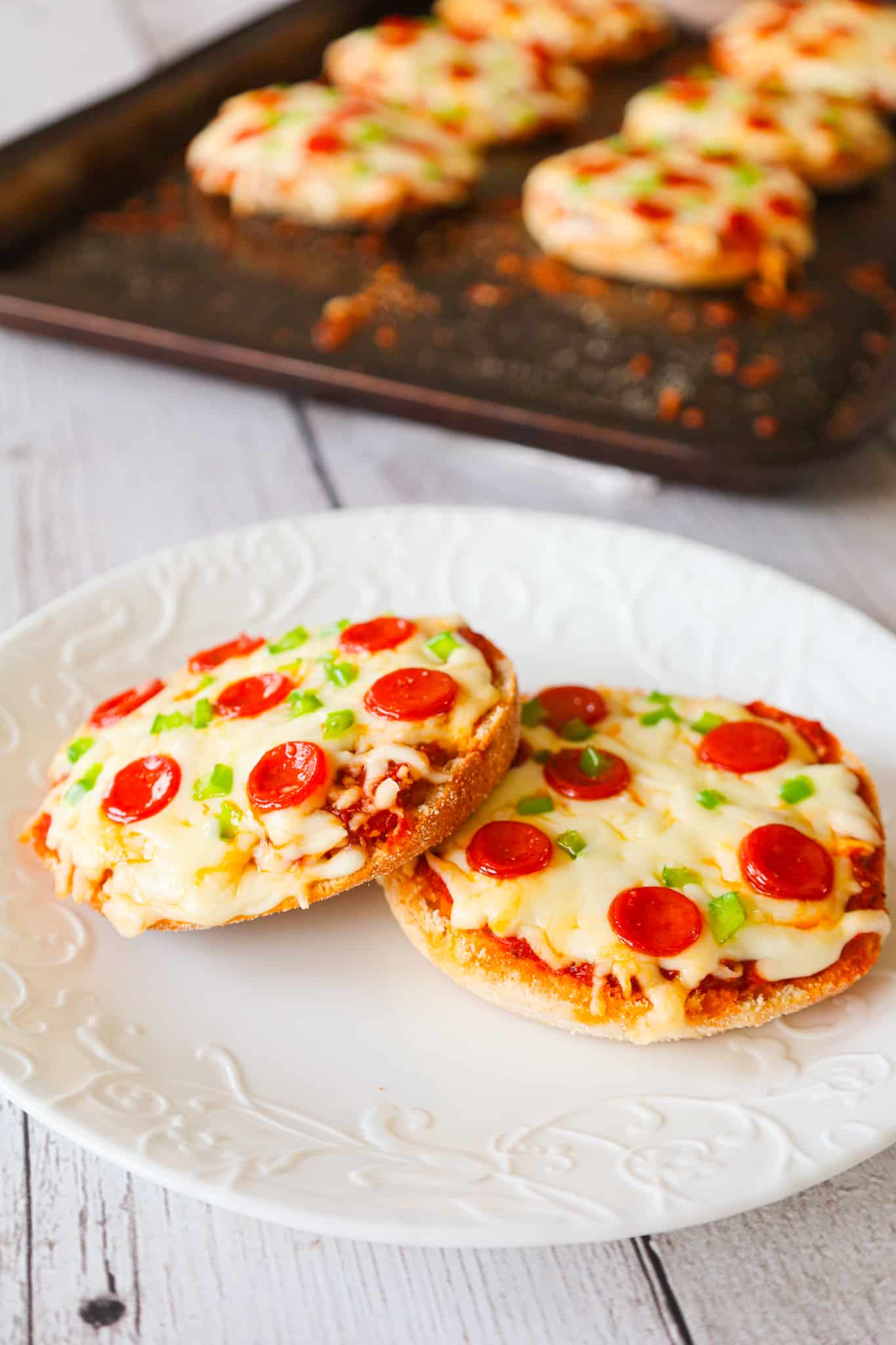 English Muffin Pizzas are an easy dinner recipe made with split English muffins topped with pizza sauce, shredded mozzarella cheese, mini pepperonis and diced green peppers.