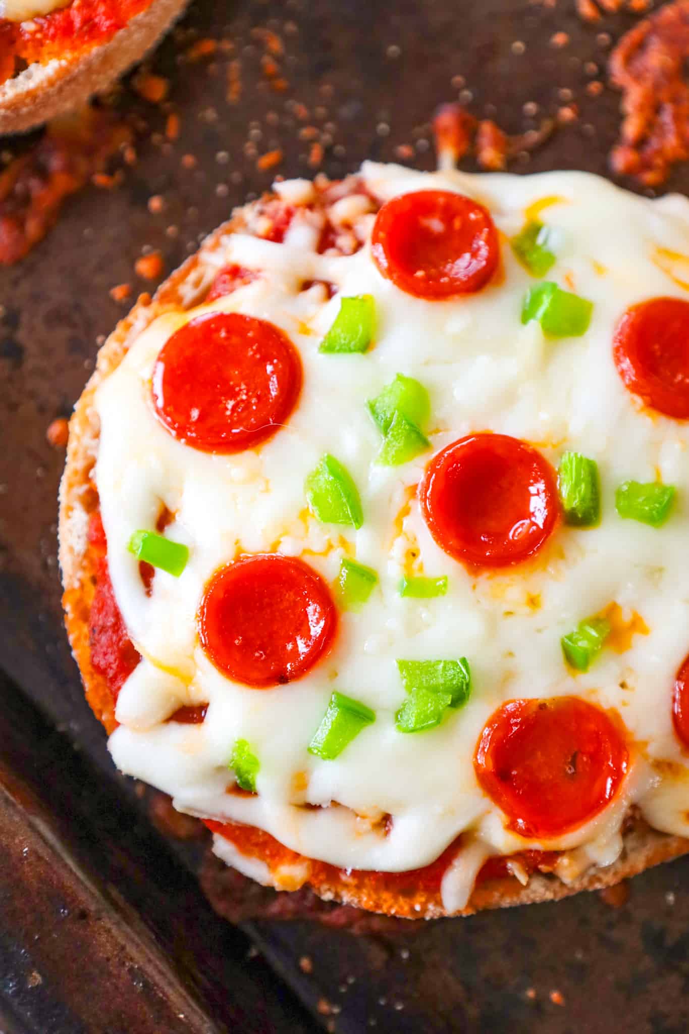 English Muffin Pizzas are an easy dinner recipe made with split English muffins topped with pizza sauce, shredded mozzarella cheese, mini pepperonis and diced green peppers.