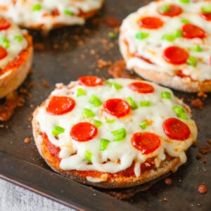 English Muffin Pizzas are an easy dinner recipe made with split English muffins topped with pizza sauce, shredded mozzarella cheese, mini pepperonis and diced green peppers.