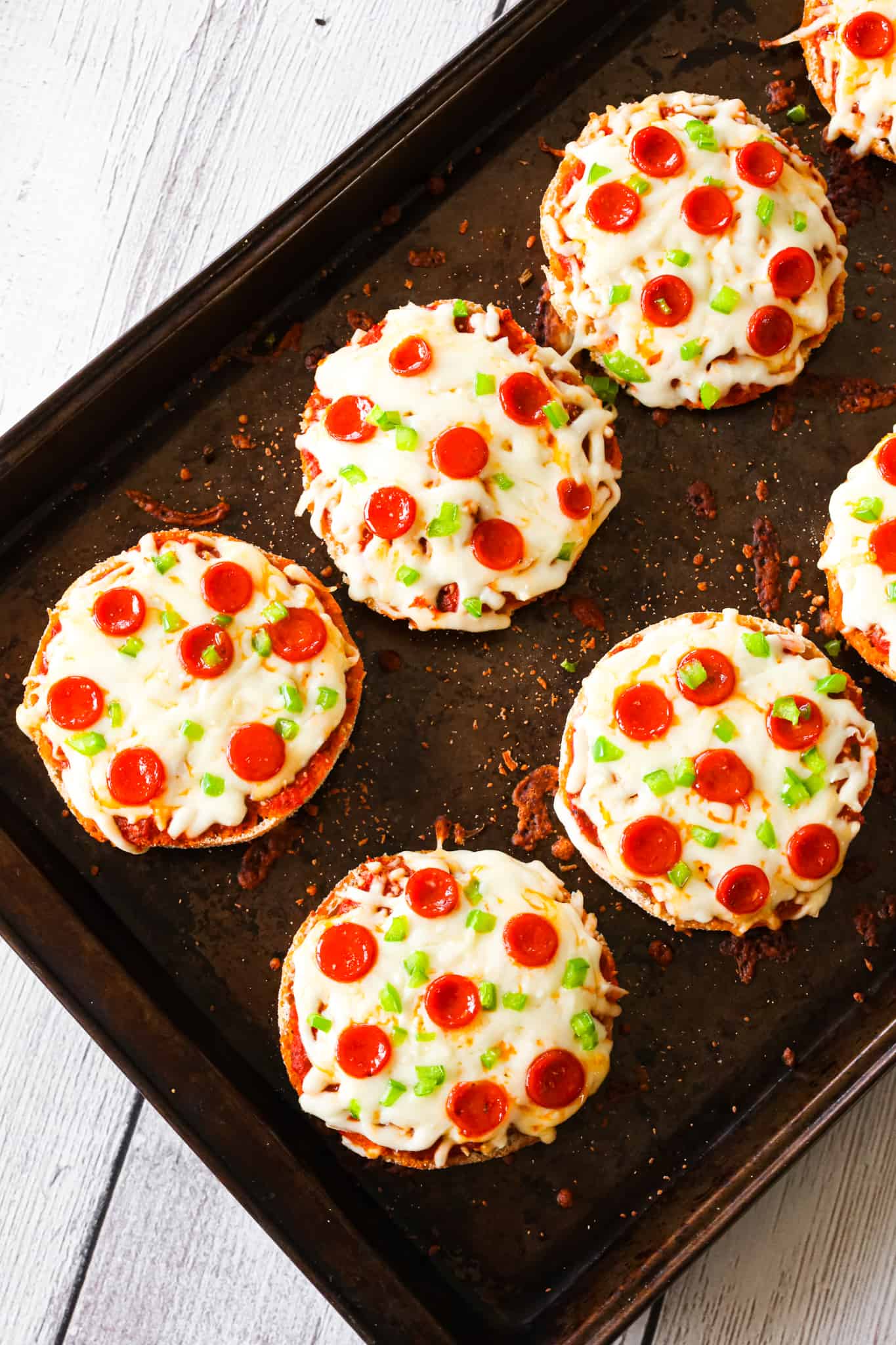 English Muffin Pizzas are an easy dinner recipe made with split English muffins topped with pizza sauce, shredded mozzarella cheese, mini pepperonis and diced green peppers.