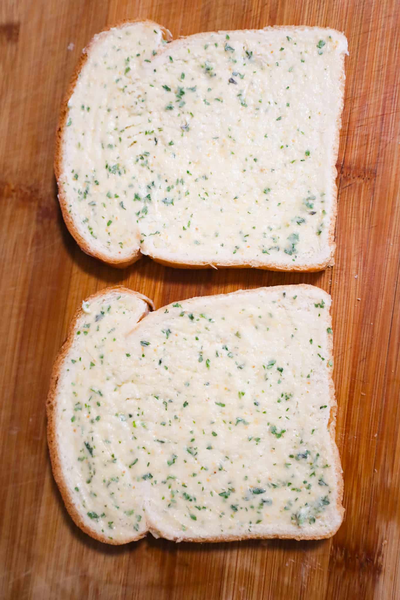 slices of bread spread with garlic butter on a cutting board