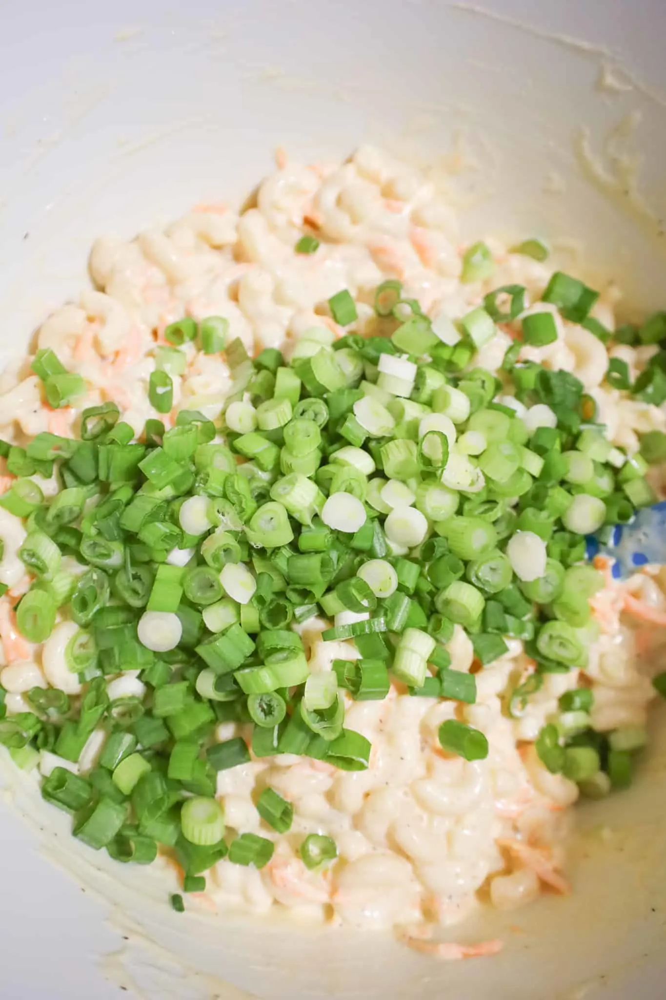 chopped green onions on top of creamy macaroni mixture in a mixing bowl