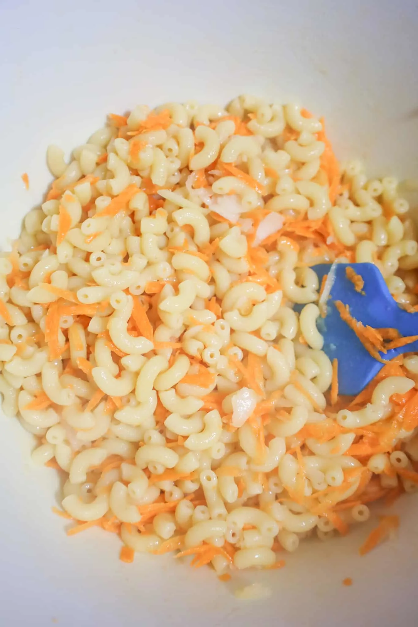 macaroni and grated carrot stirred together in a mixing bowl