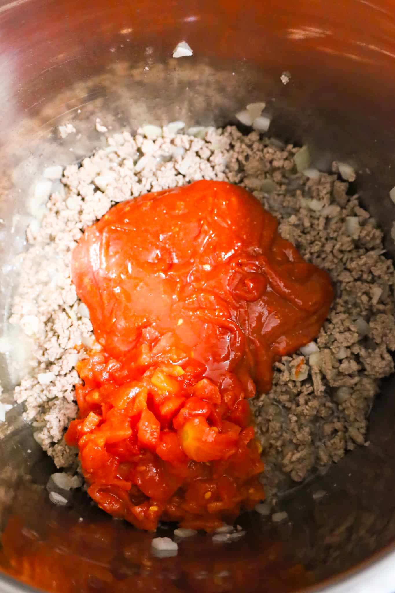 diced tomatoes and sloppy joe sauce on top of crumbled ground beef in an Instant Pot