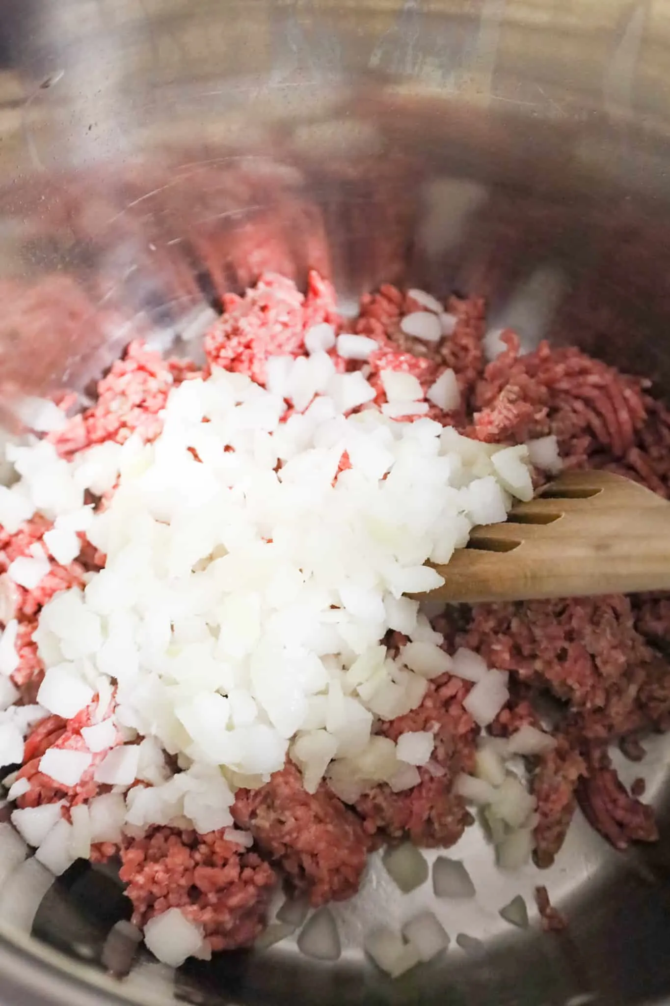 diced onions on top of raw ground beef in an Instant Pot