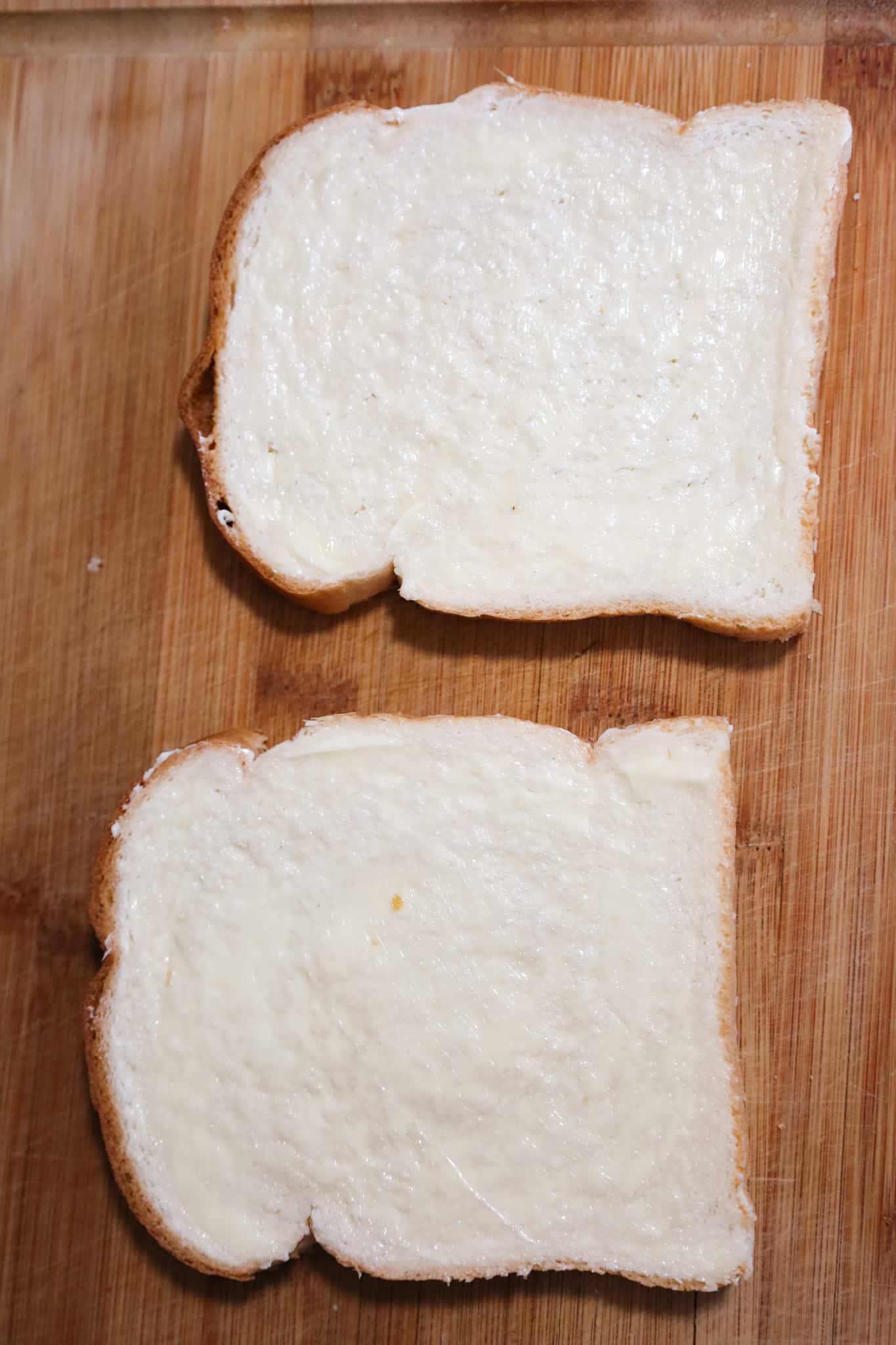 butter spread on slices of bread on a cutting board