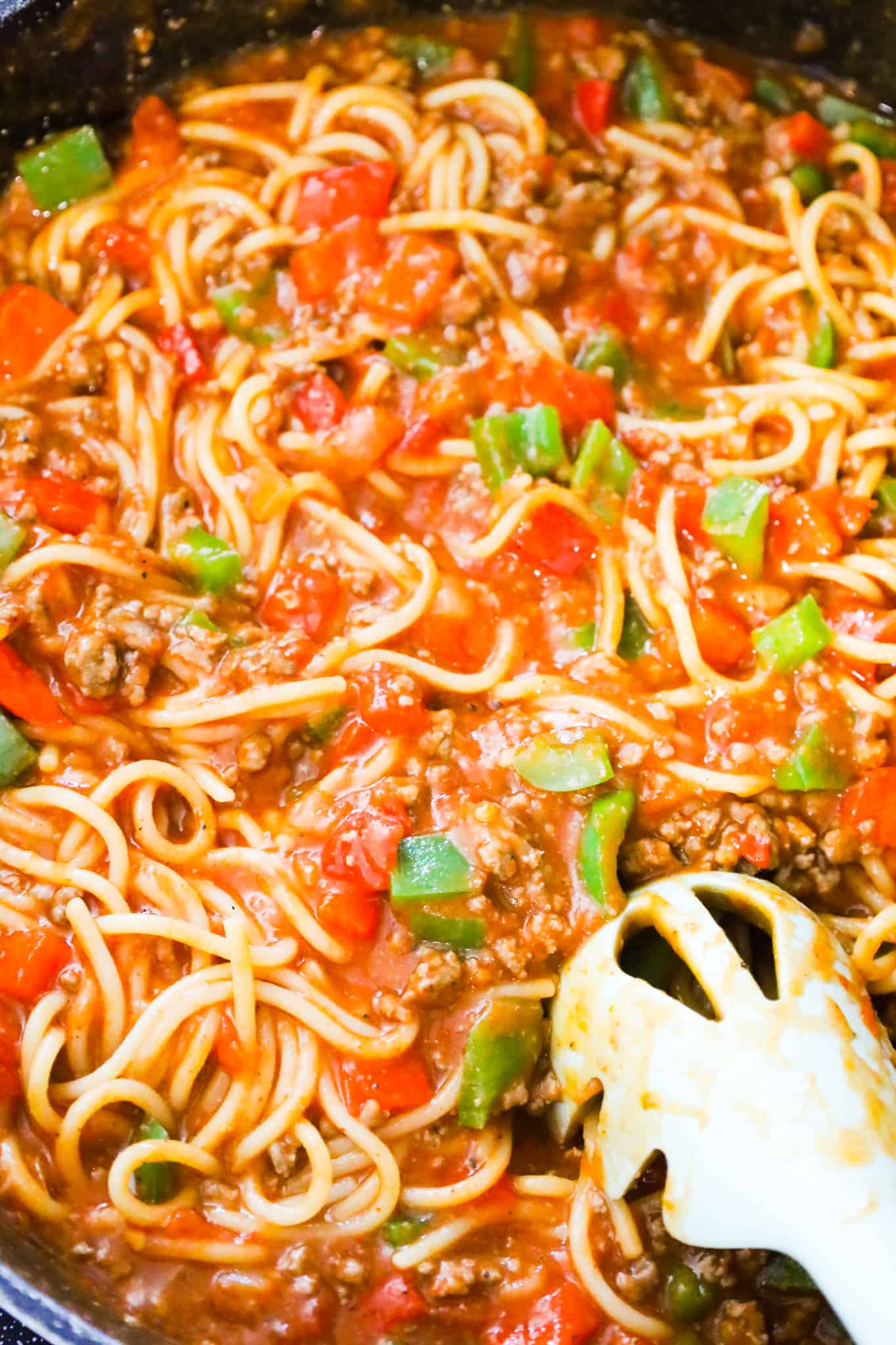 Mexican Spaghetti is a hearty pasta recipe loaded with ground beef, red peppers, green peppers, onions, Rotel diced tomatoes and green chilies, taco seasoning and shredded cheese.