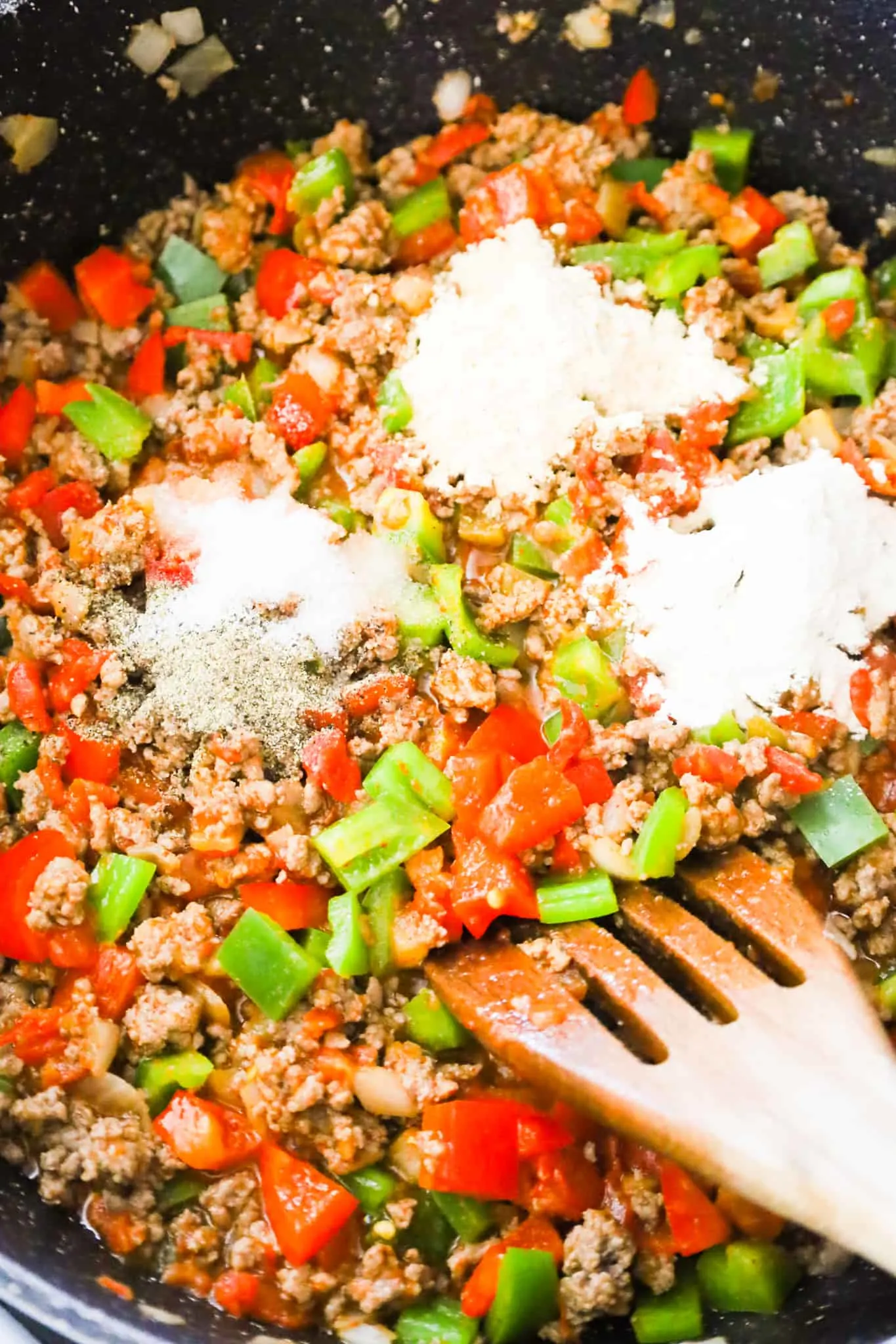 spices on top of ground beef and peppers mixture in a saute pan