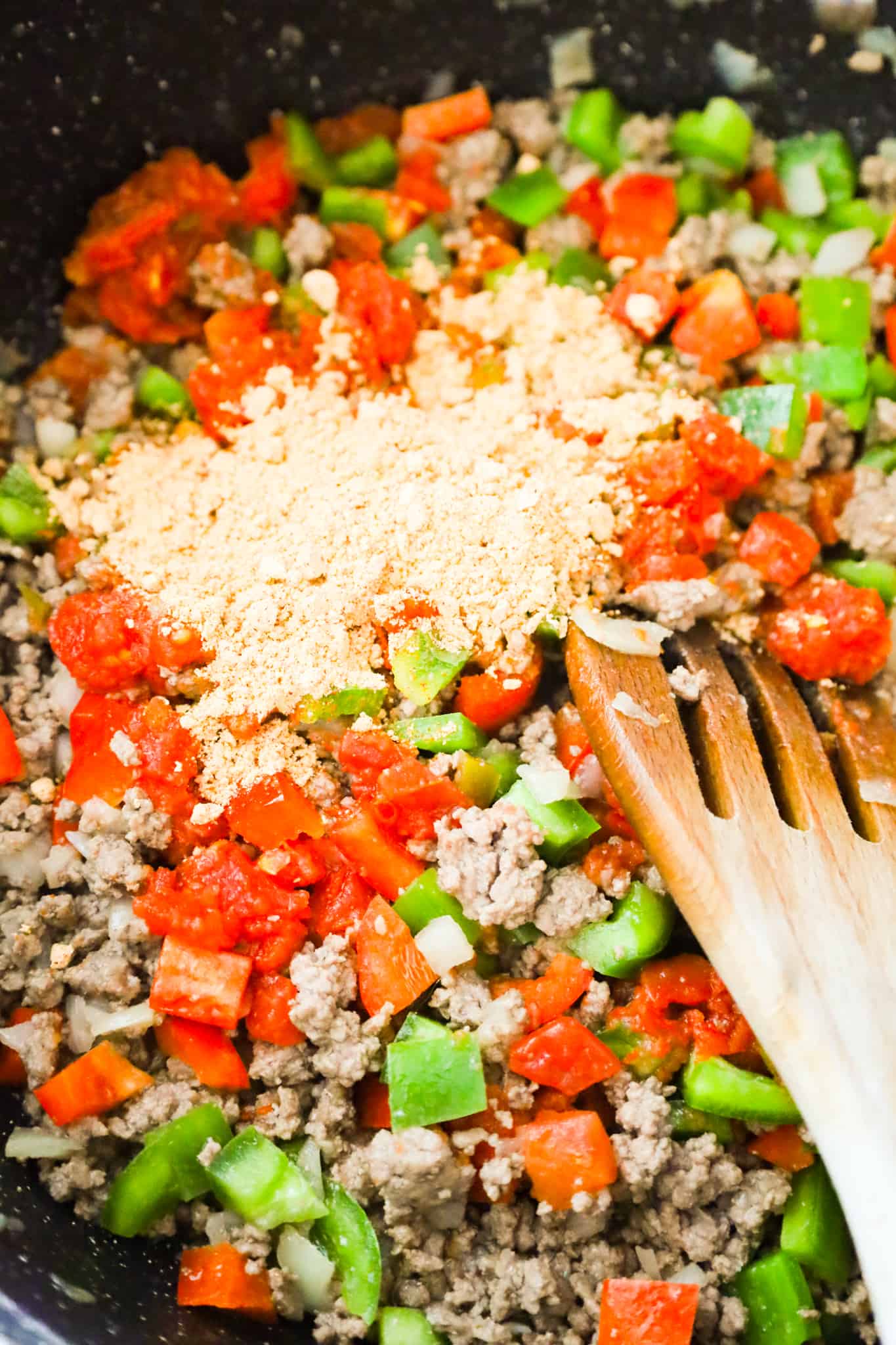 taco seasoning on top of cooked ground beef and diced peppers mixture in a saute pan