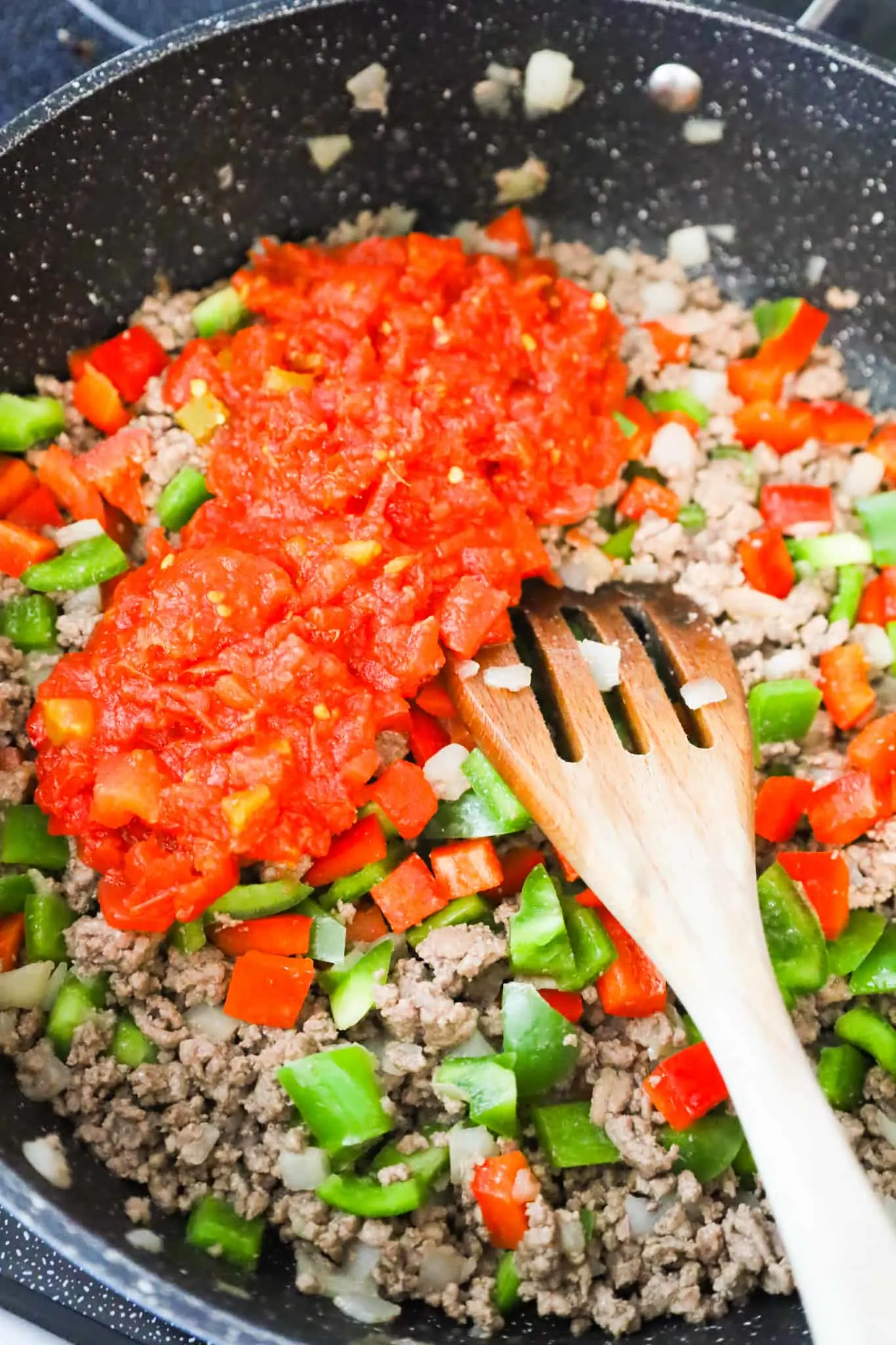 Rotel diced tomatoes on top of cooked ground beef and diced peppers mixture