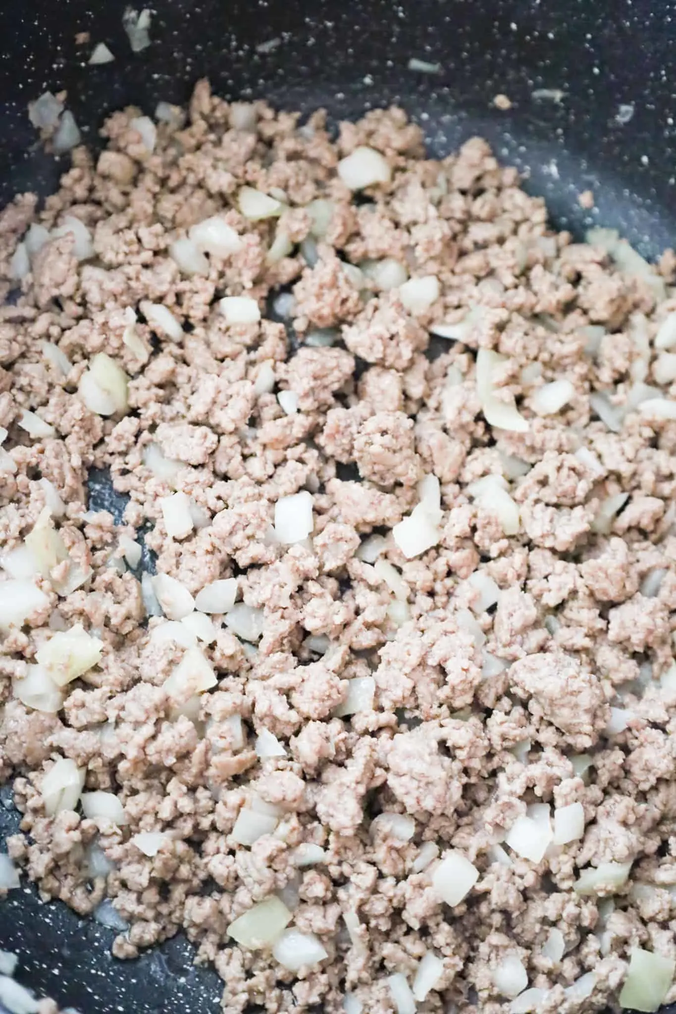 cooked ground beef in a saute pan with diced onions