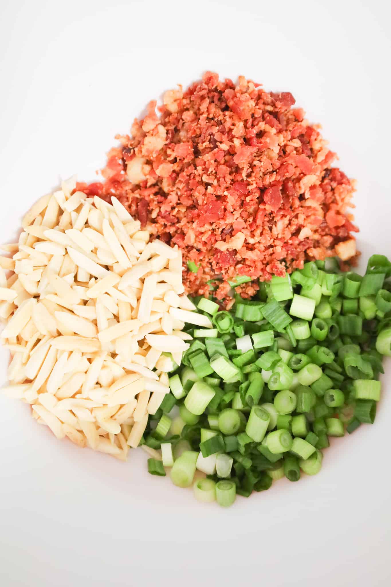 slivered almonds, chopped green onions and crumbled bacon in a mixing bowl