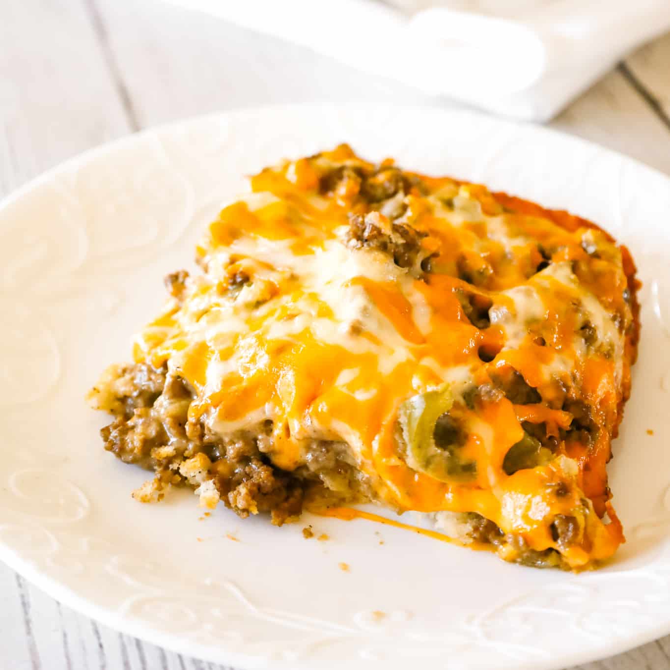 Philly Cheese Steak Casserole is an easy ground beef casserole recipe with a Bisquick base and loaded with green peppers, onions, mozzarella and cheddar cheese.