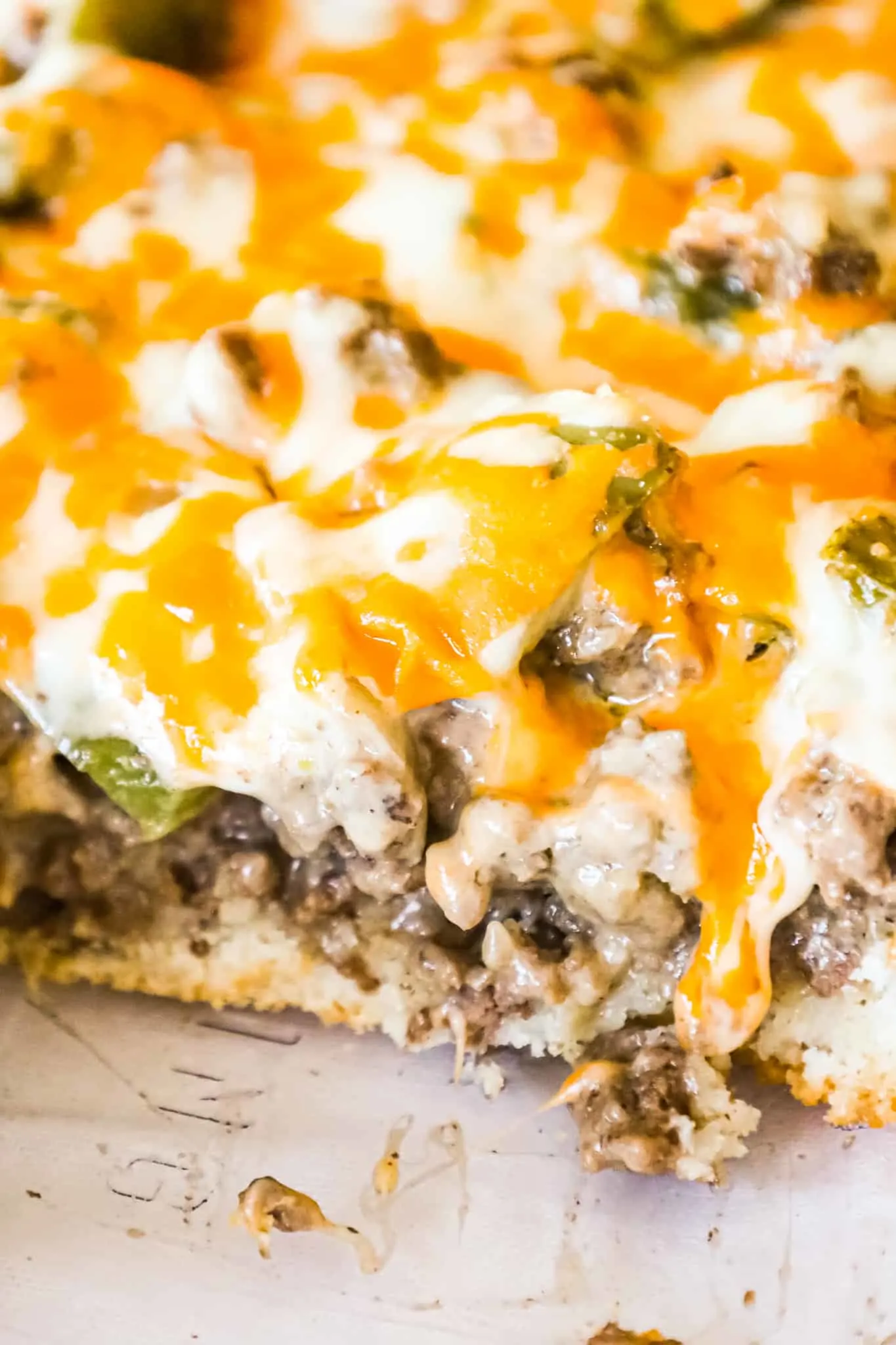 Philly Cheese Steak Casserole is an easy ground beef casserole recipe with a Bisquick base and loaded with green peppers, onions, mozzarella and cheddar cheese.