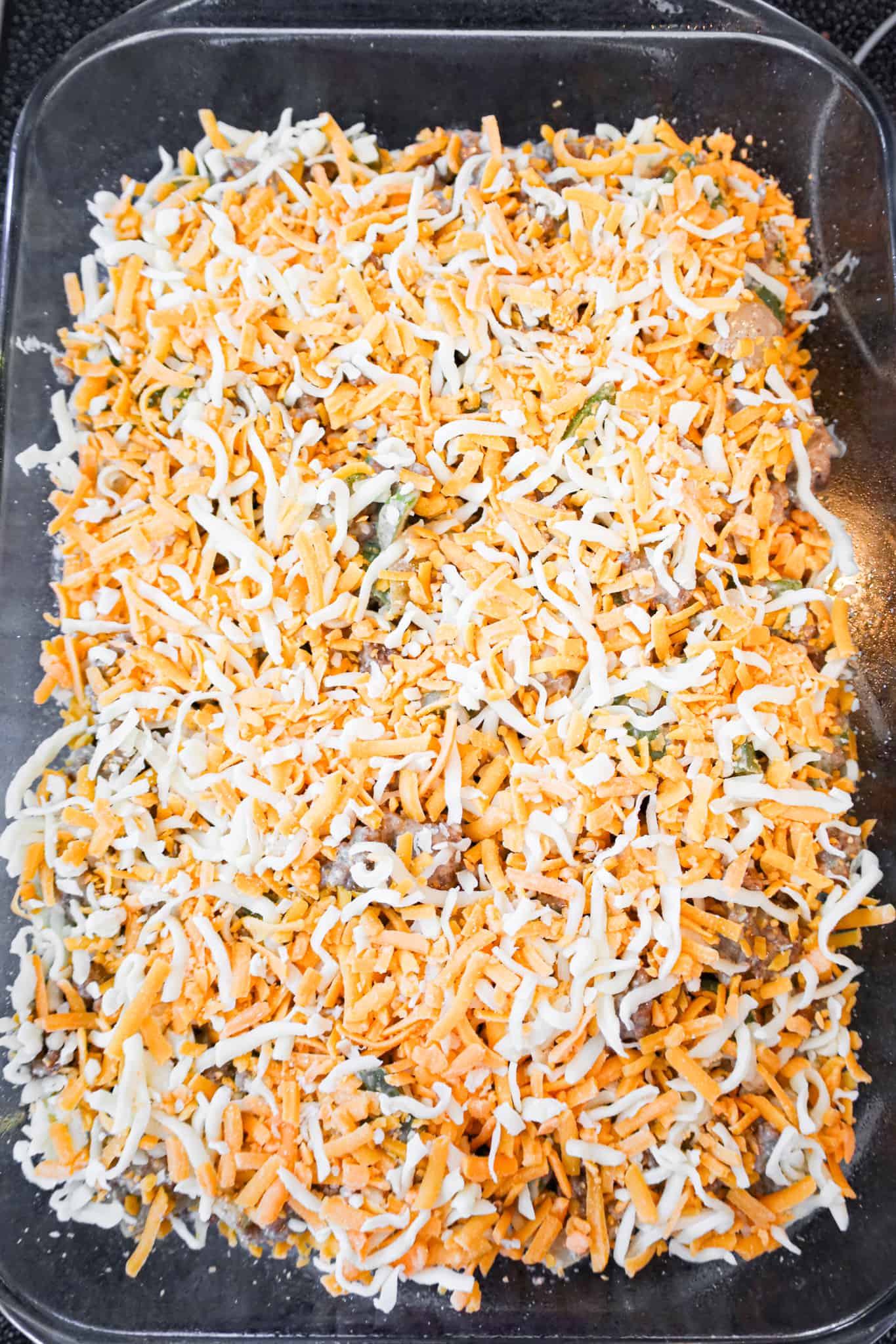 shredded cheese on top of philly cheese steak casserole before baking